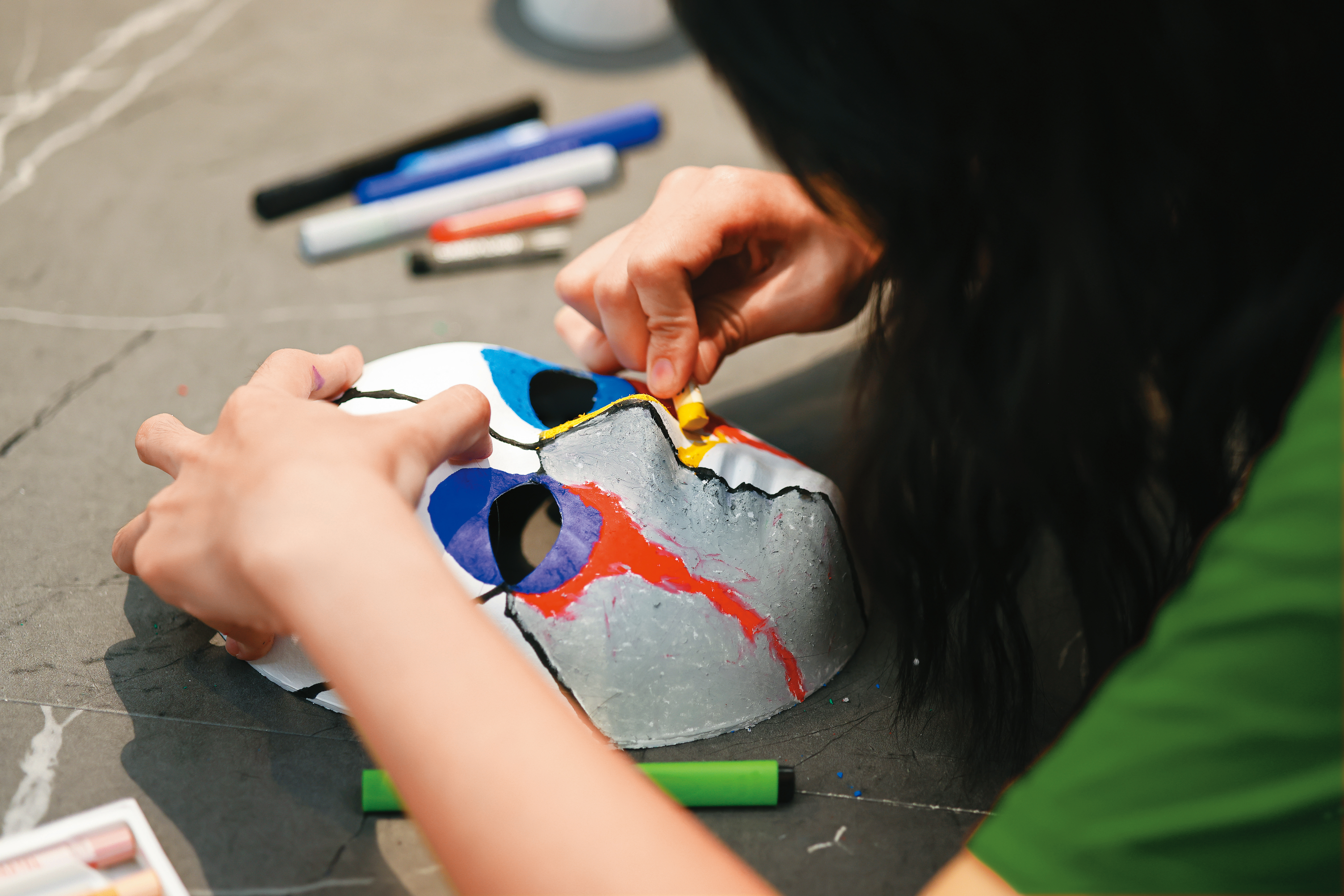 長達40分鐘，小云細心繪製面具，雙手沾滿蠟筆粉末。