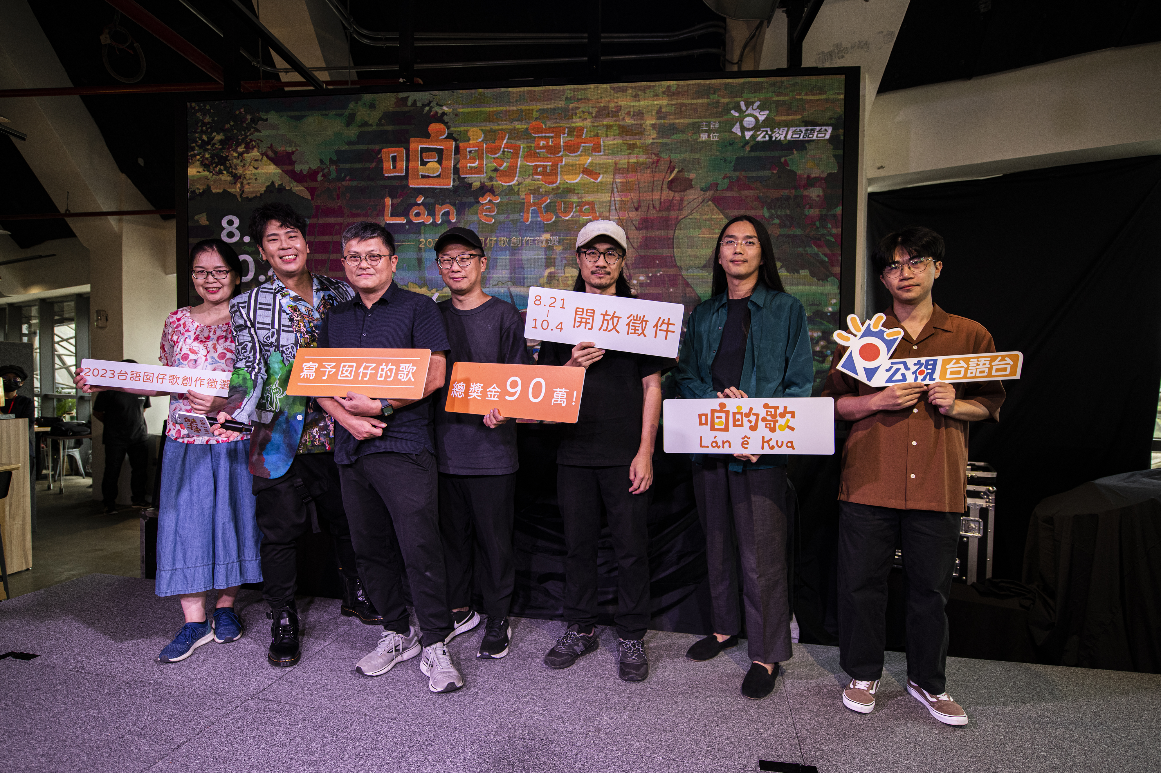 代言人邵大倫（左二）、製作人黃培育（左三）、柯智豪（中）、曾仁義（右三）、邀請曲作詞者王秀容（左一）、《百合花》主唱林奕碩（右二）、《裝咖人》團長張嘉祥（右三）力邀大家來投件。（公視台語台提供）