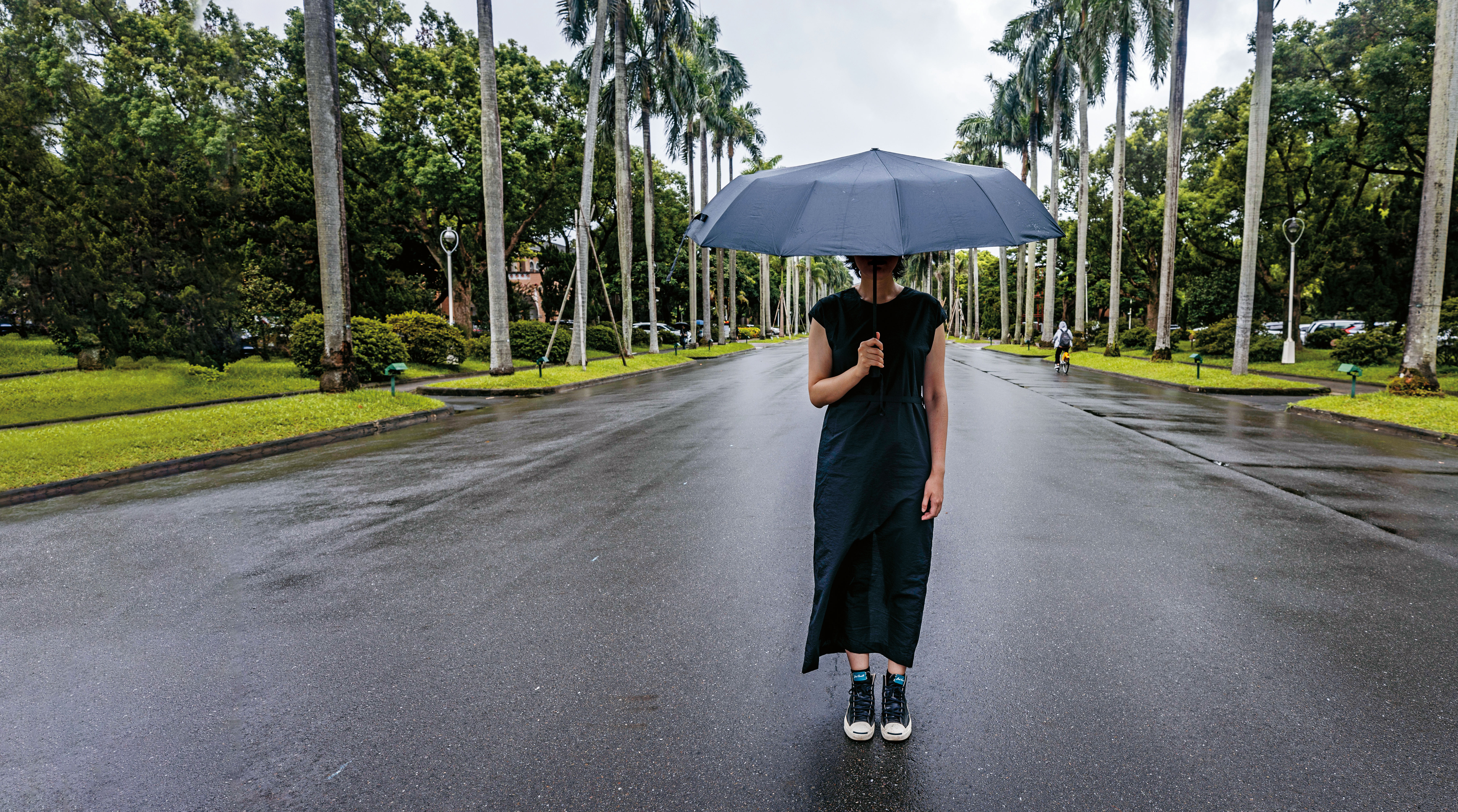 小淨在椰林大道上撐起傘。