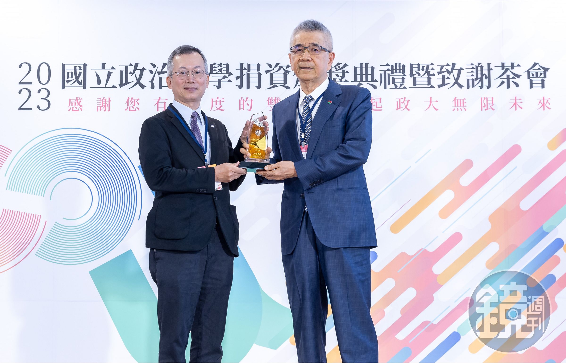 信義企業集團創辦人周俊吉(右)從政大校長李蔡彥手中接下感謝獎座。(信義房屋提供)