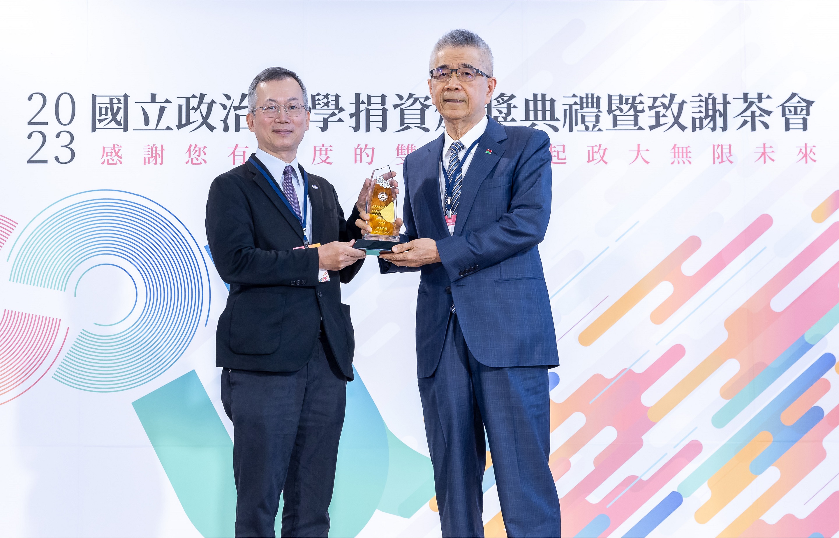 信義企業集團創辦人周俊吉（右）從政大校長李蔡彥手中接下感謝獎座。（信義房屋提供）