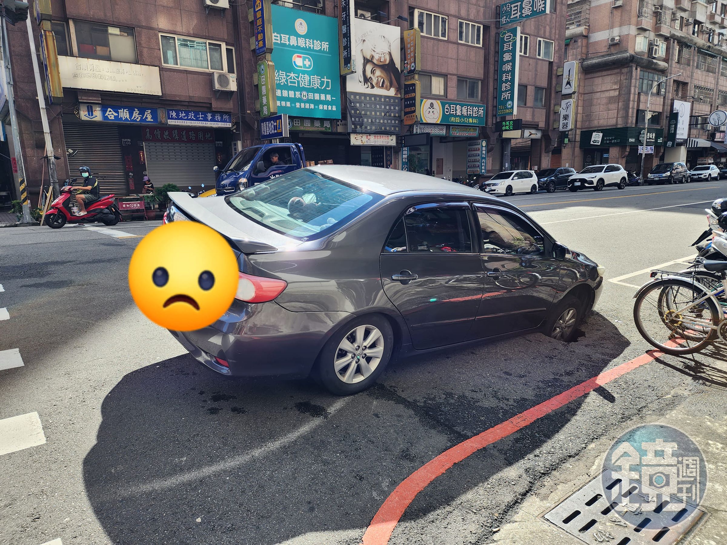 台中南區學府路上，今天有車子的右前輪被天坑吞噬，導致整台車輛動彈不得。（翻攝自爆料公社）