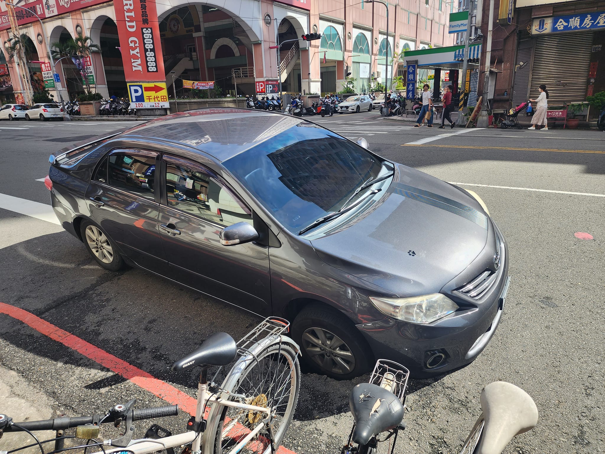台中南區學府路上，今天有車子的右前輪被天坑吞噬，導致整台車輛動彈不得。（翻攝自爆料公社）
