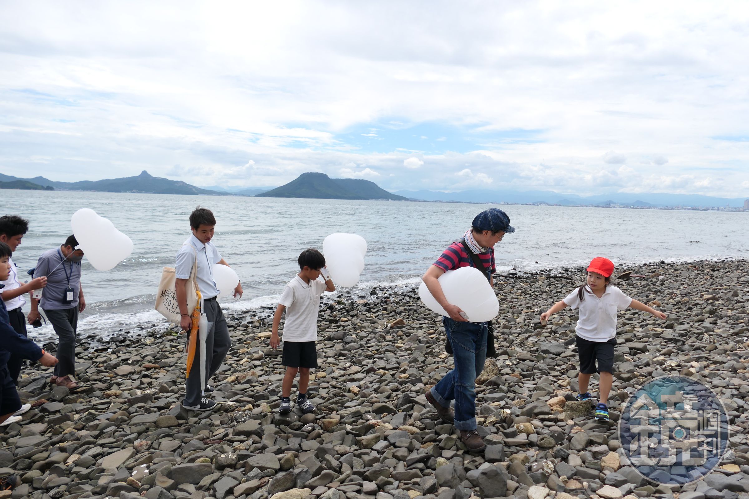 日本藝術家高橋匡太帶著男木島學生在海邊撿石頭，此後他將把這些石頭帶到馬祖，讓男木島的土地成為作品的一部分。（文總提供）