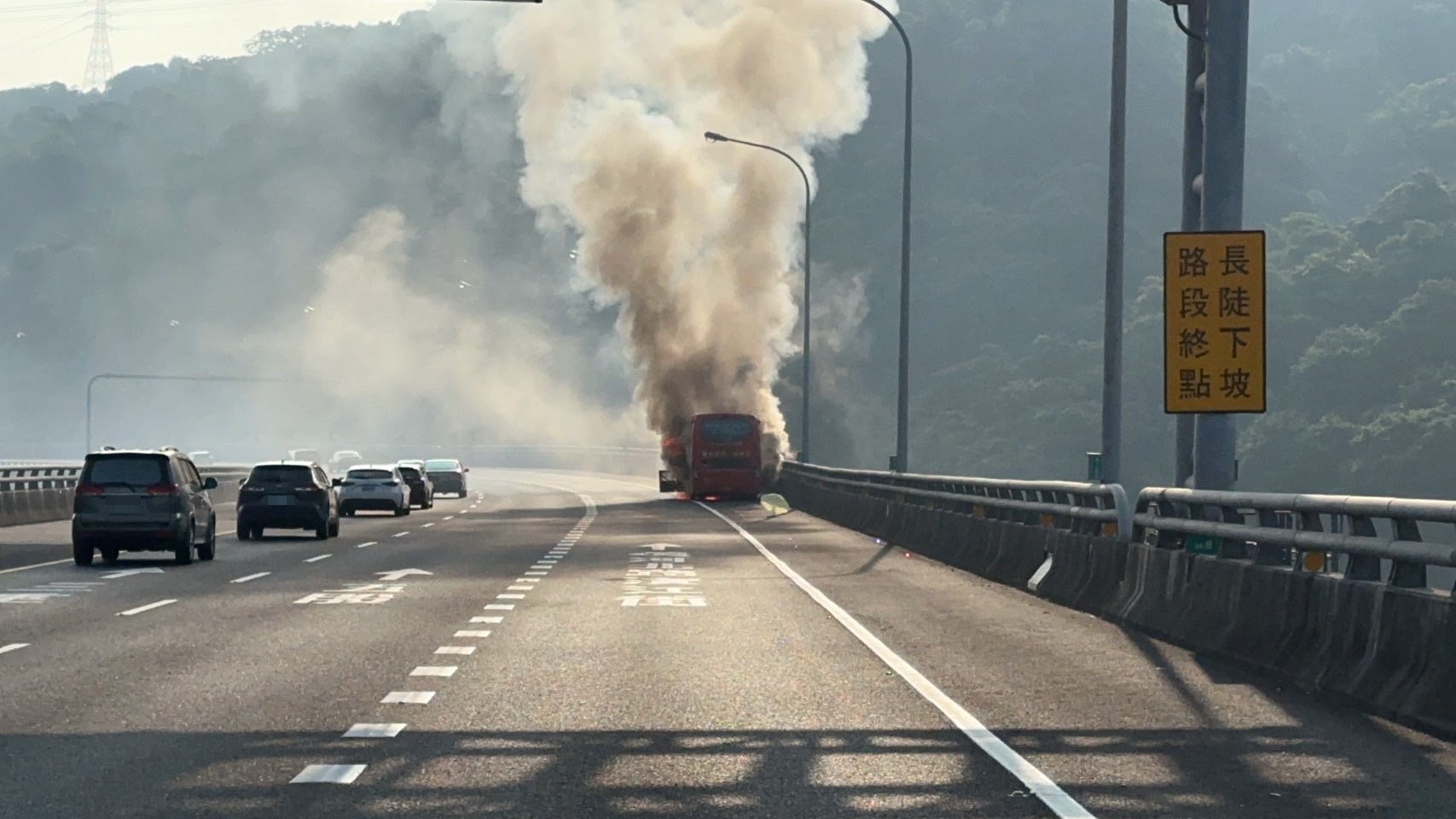 遊覽車董姓駕駛發現車輛冒煙，緊急將車停靠路肩，車輛隨即起火燃燒。（翻攝畫面）