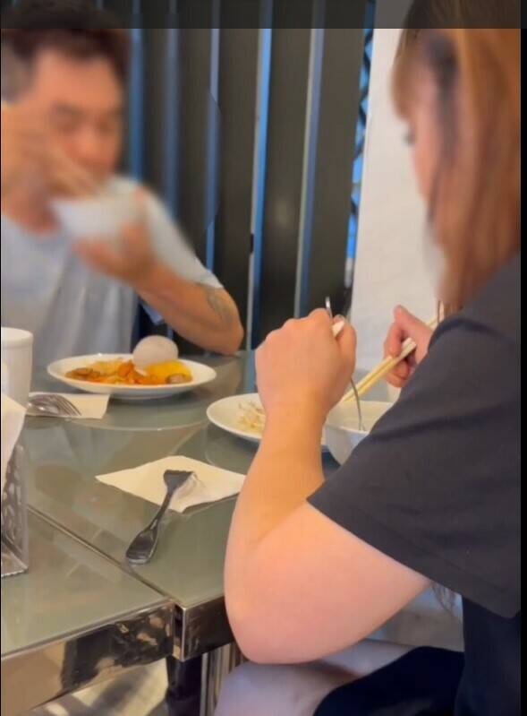 警察拘捕時，洪男與女友悠閒繼續吃早餐，一臉不甩警察的神情。（翻攝畫面）