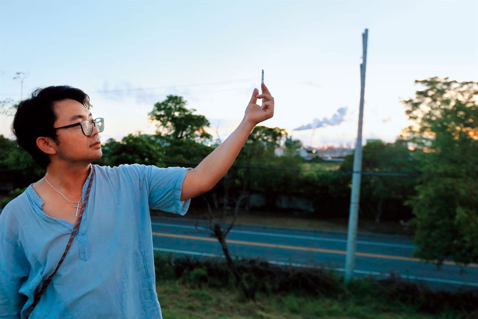 在林園工業區煙囪前照相,他說:「我抽不健康的菸,後面是更大的(不確定健康與否)的煙。」(高雄文學館攝影/吳妖妖提供)