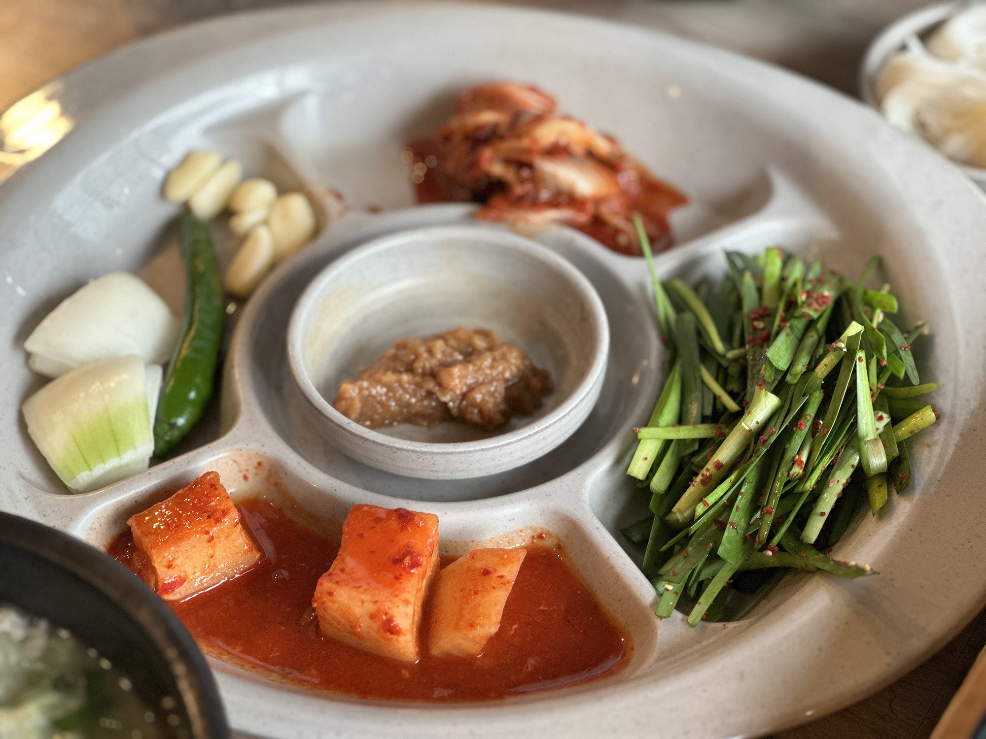 搭配湯飯的小菜有醃漬涼拌韭菜、白蘿蔔辛奇、大醬、生蒜頭等。