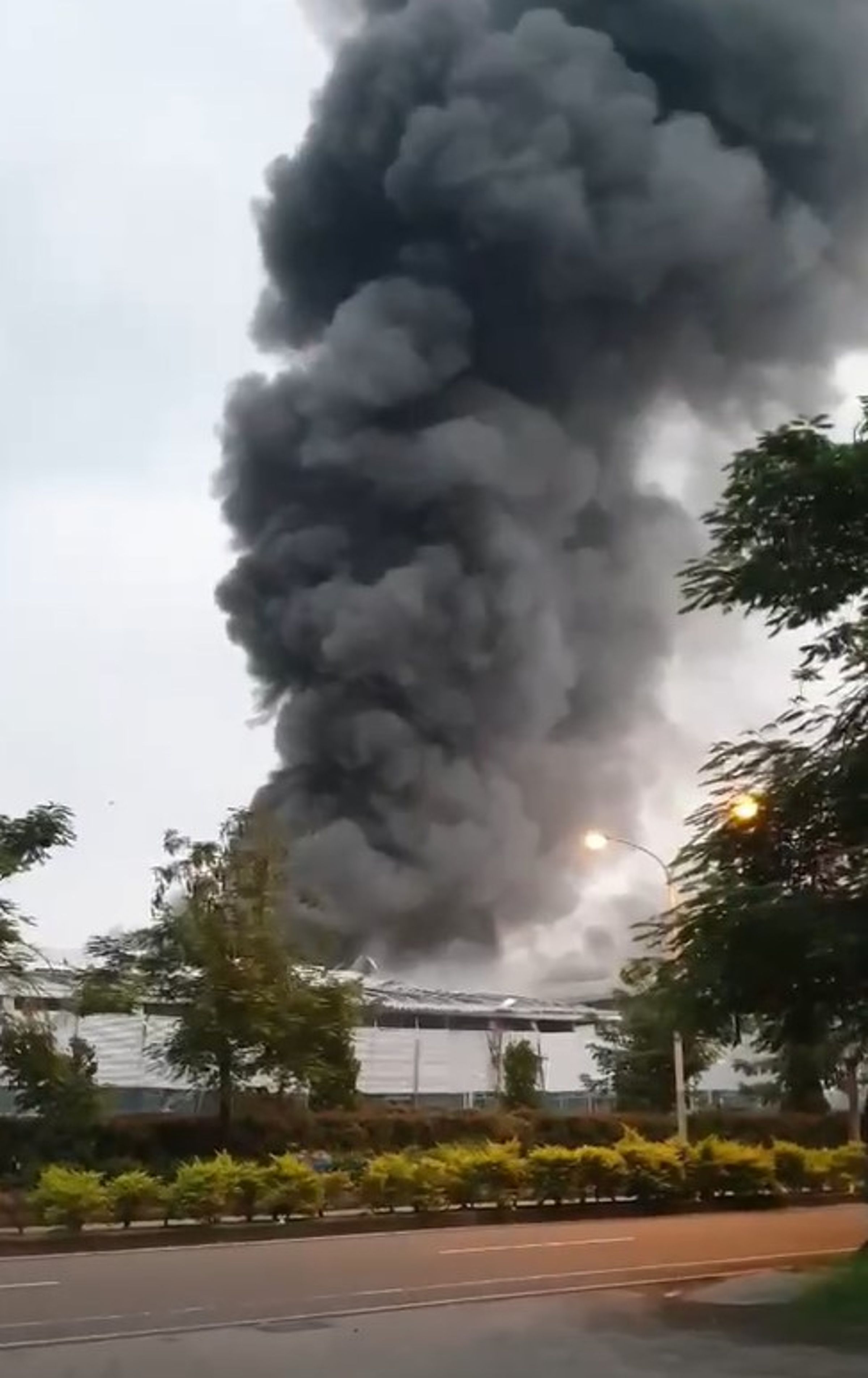 明揚國際廠房昨晚爆炸起火,引來員工圍觀,火勢越燒越大後民眾趕忙穿越停車場離開現場。(翻攝自鄭榮貴臉書)