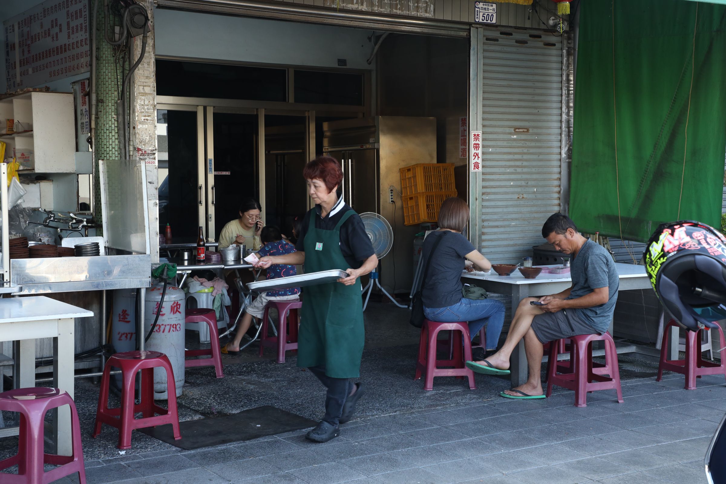 店員遊走在兩個店面騎樓下送餐。