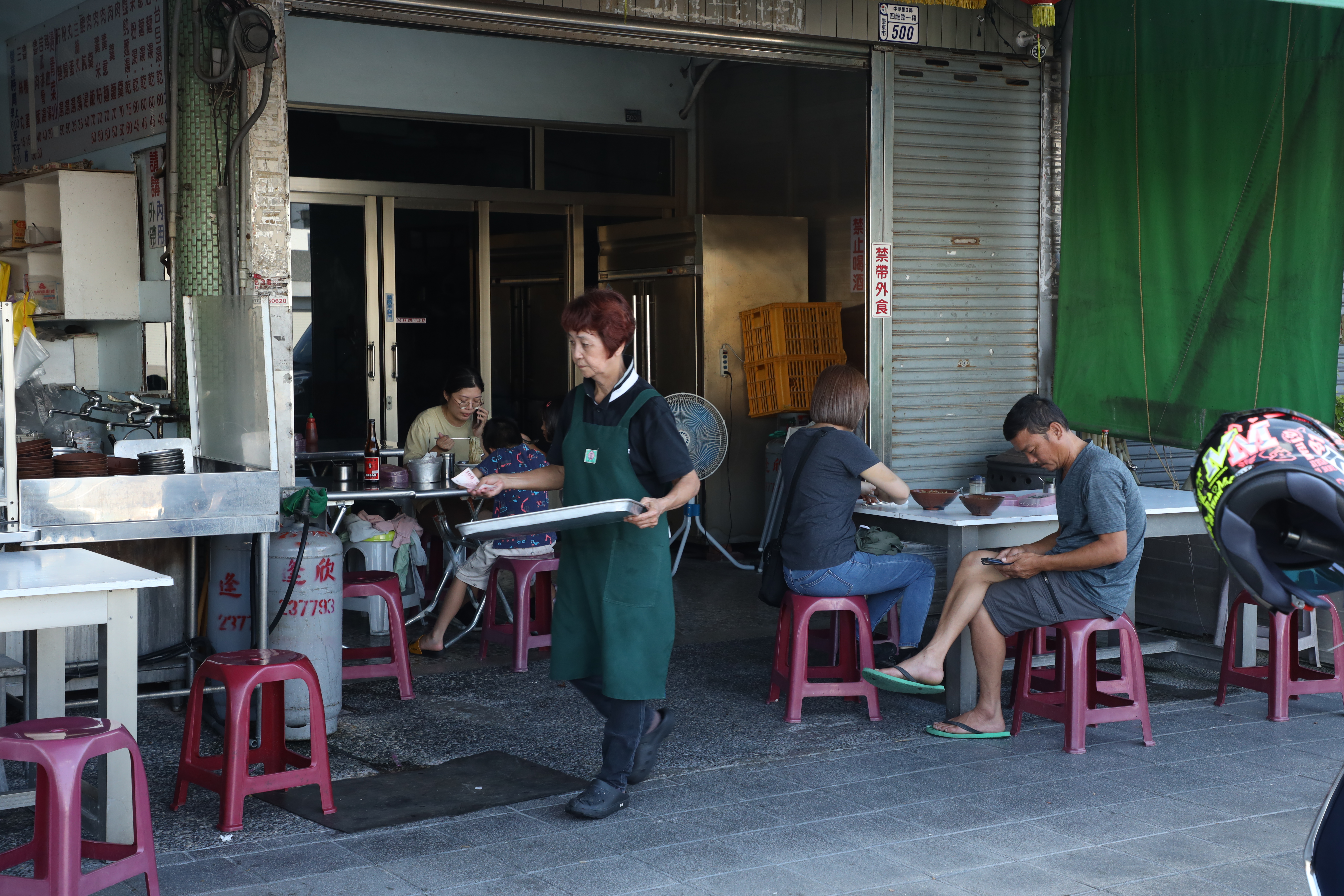 店員遊走在兩個店面騎樓下送餐。