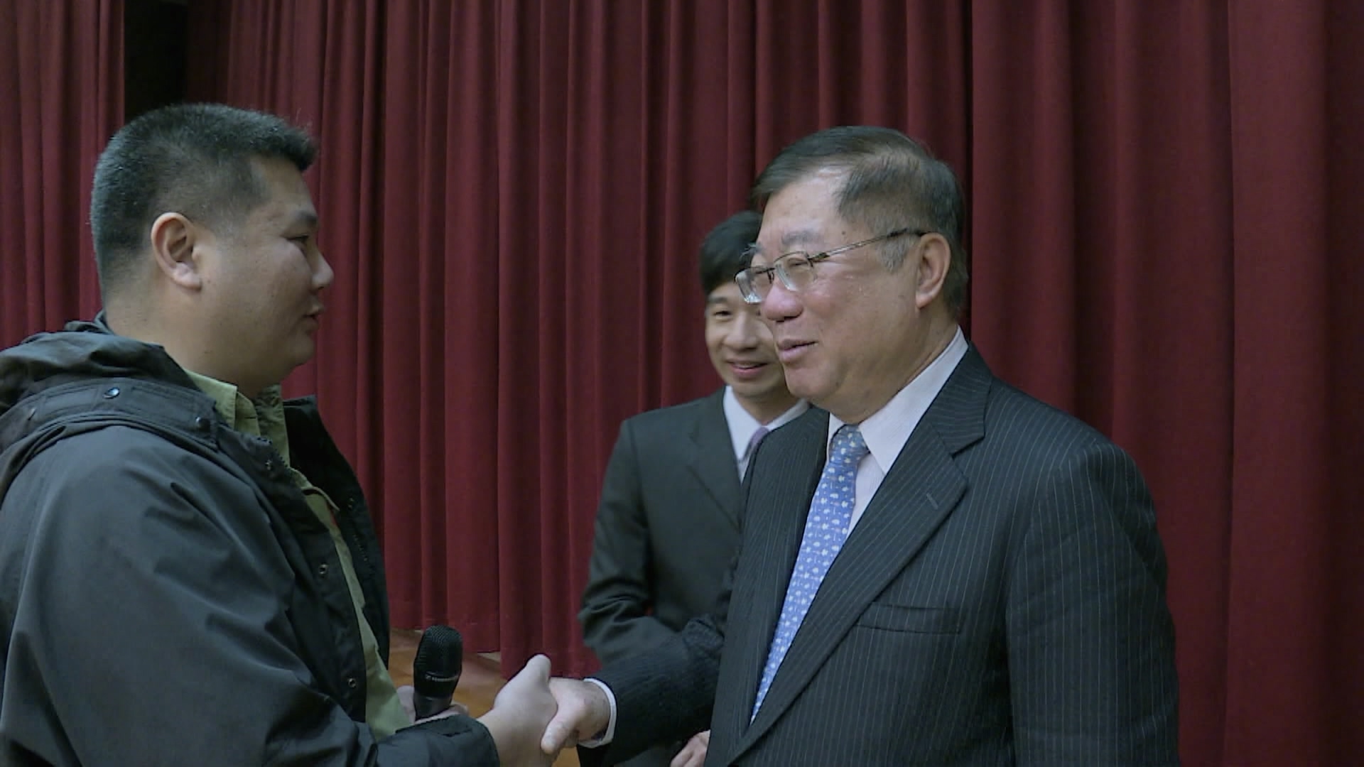 李惠仁(左)現身時任農委會(現為農業部)主委陳保基(右)的卸任歡送會,並抓住機會追問禽流感疫情失控的議題。(公視提供)
