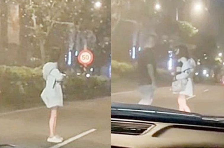 這名妹子站在馬路中央險象環生，一名黑衣男緊急下車救援。（翻攝自社會事新聞影音）