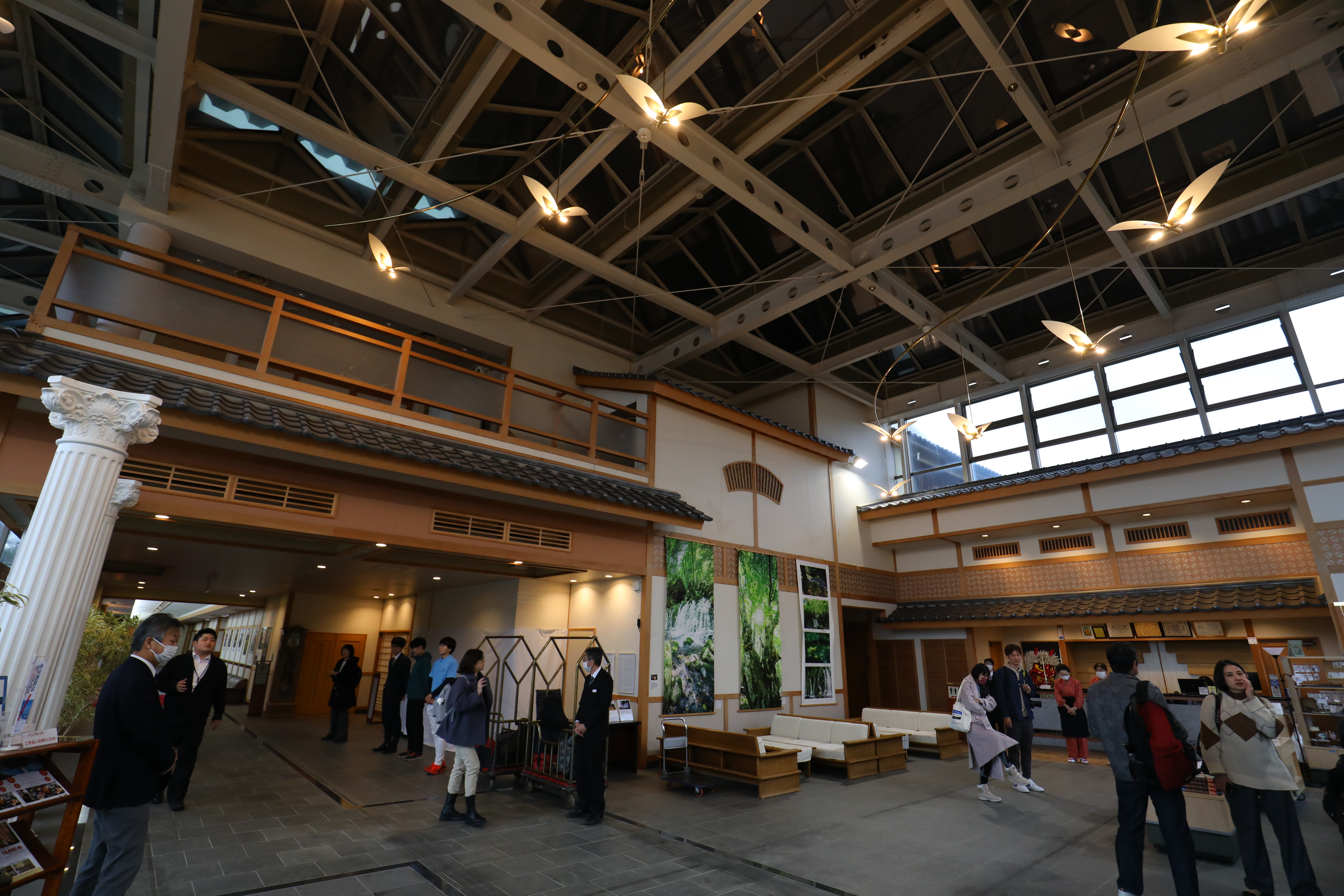 旅館挑高大廳以古典和風裝飾，有年輕服務員也有資深旅館人員。