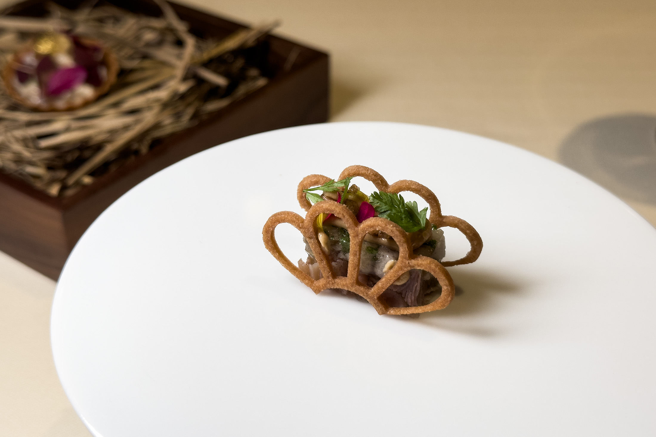 「鴨肉凍派／山芋頭／松子」將油封鴨肉、屏東小山芋與慢火燉煮的高湯製成肉凍，夾入兩片芋頭脆片中，鹹味與鮮味將味蕾喚醒，開啟感官。（午、晚間套餐菜色1,880元起／人）