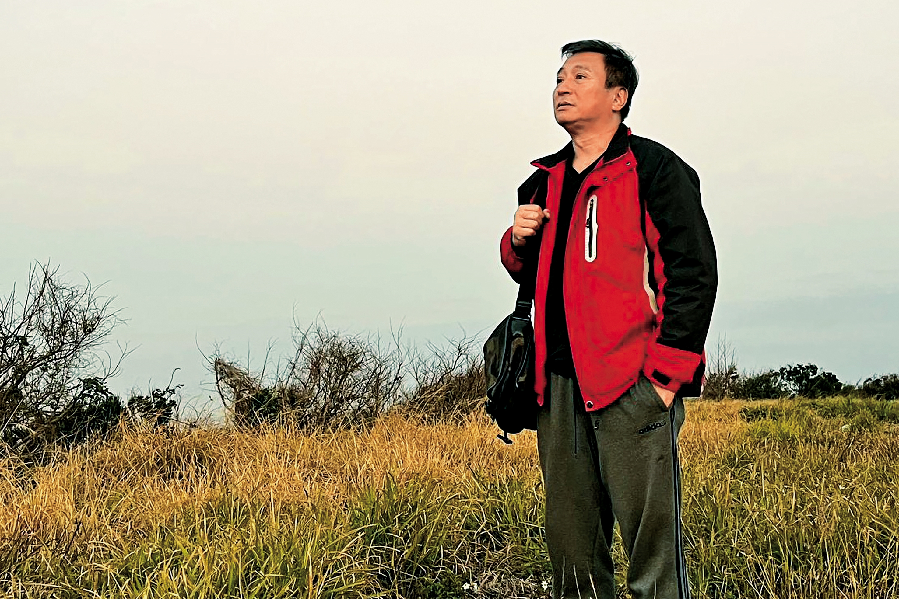 王中平站在苗栗後龍好望角的七百坪荒地上，遙望被山海圍繞的景致，並從零開始親手闢建露營區。（讀者提供）