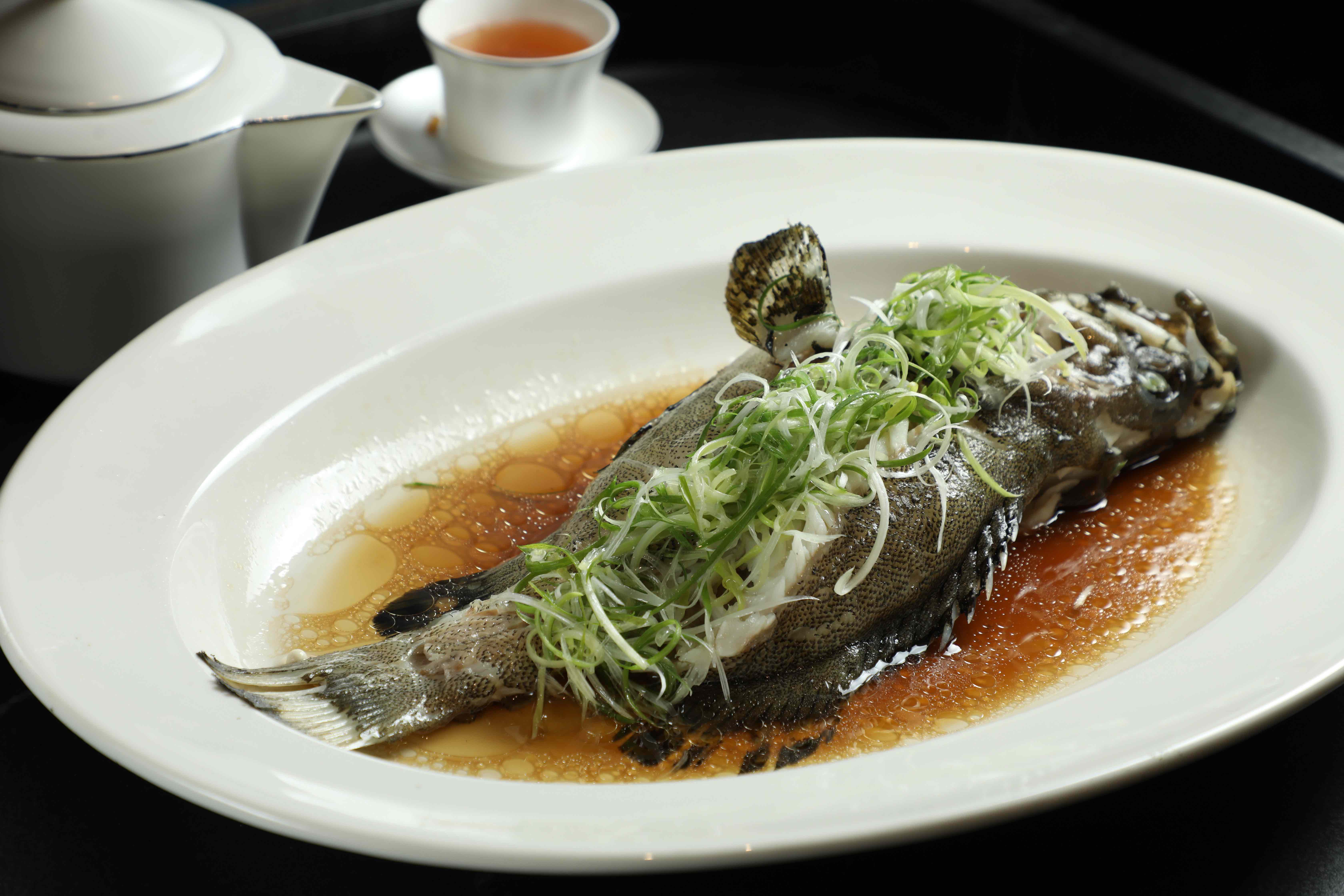 「蔥油清蒸活龍虎斑」以蔥油提香,凸顯龍虎斑鮮嫩細緻的肉質。(時價)