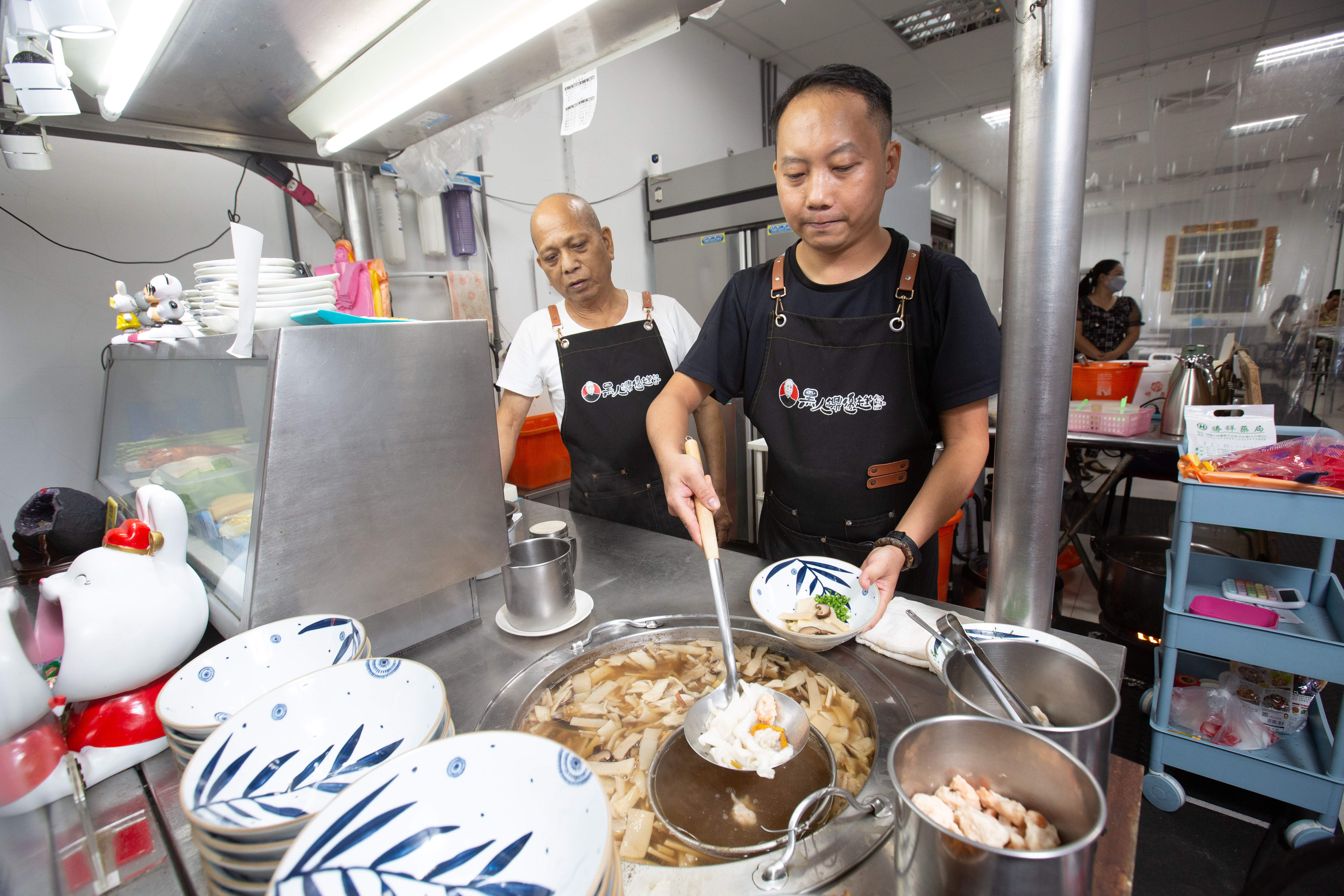 老總鋪師唐賢次（右）五十多年前在桃園街邊開始賣鼎邊趖，小兒子唐茂檳（左）7年前見父親年邁，辭去穩定工作，從頭學起接下老店。