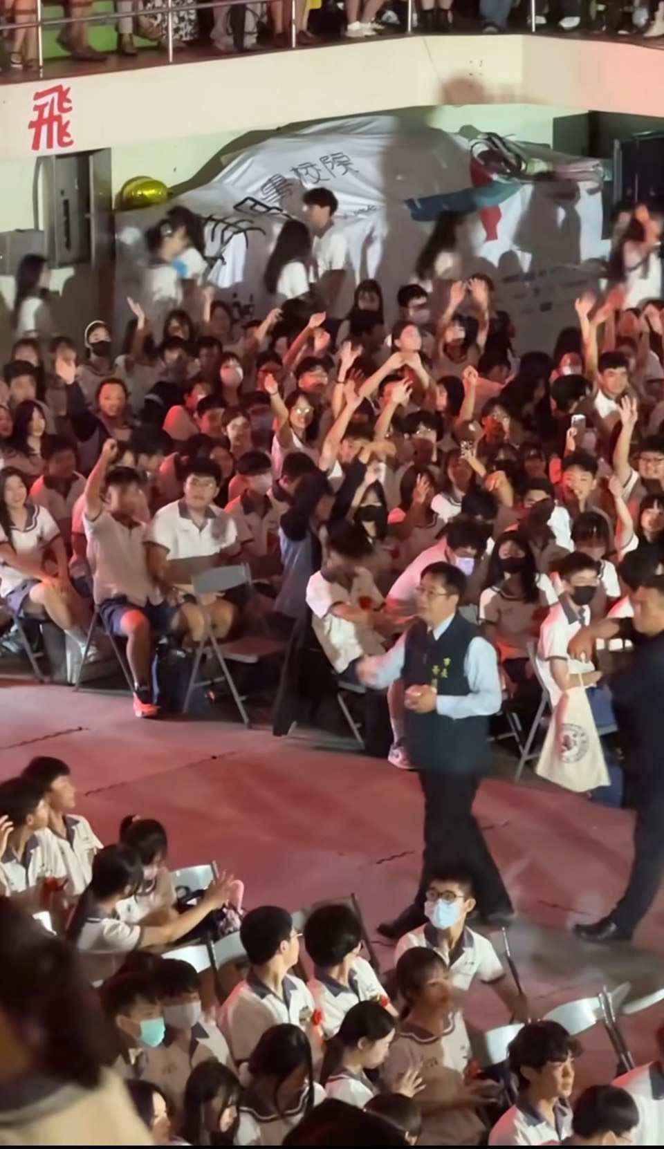 黃偉哲將畢業典禮當跨年在撒禮物,從進場走進館內一路悠哉,引起熱議。(翻攝畫面)