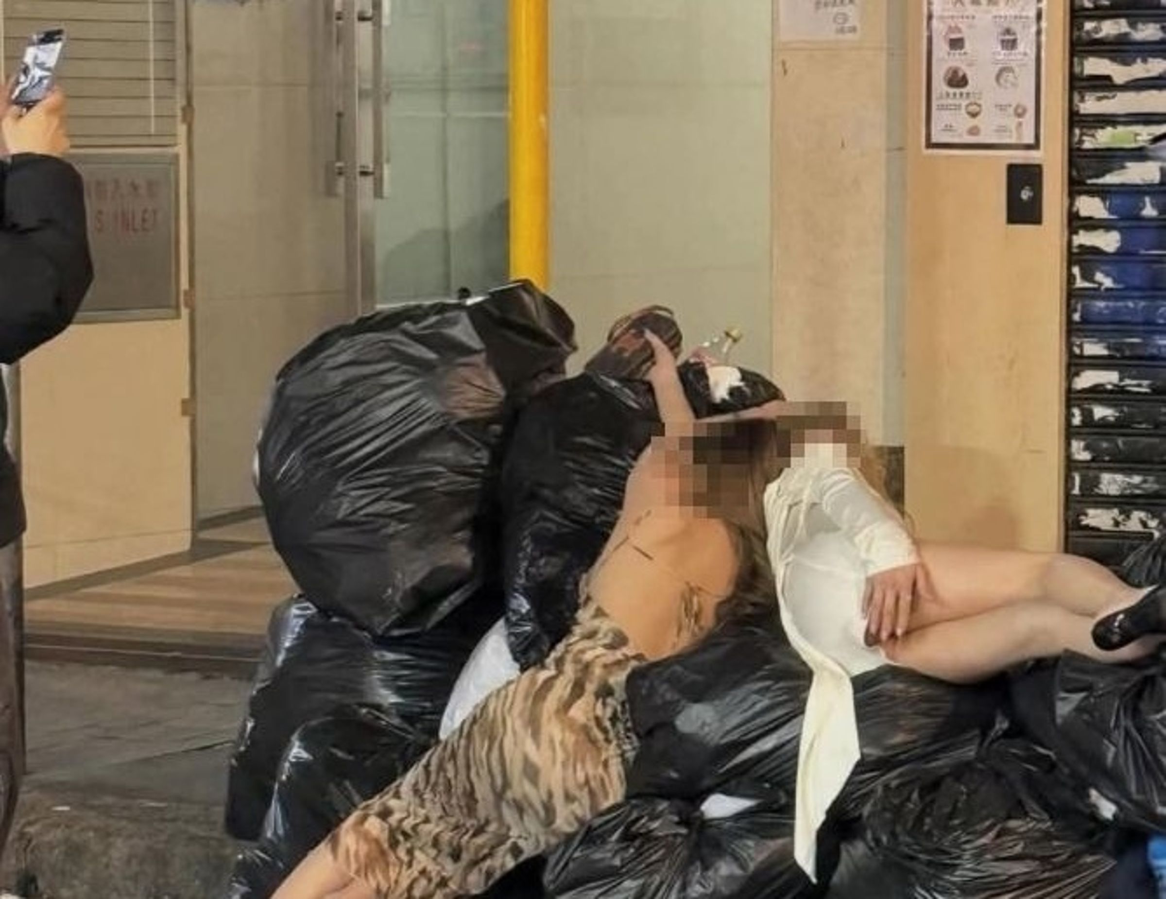 一名網友轉貼街景照片，只見2名辣妹竟躺在垃圾堆裡。（翻攝自爆廢公社臉書）