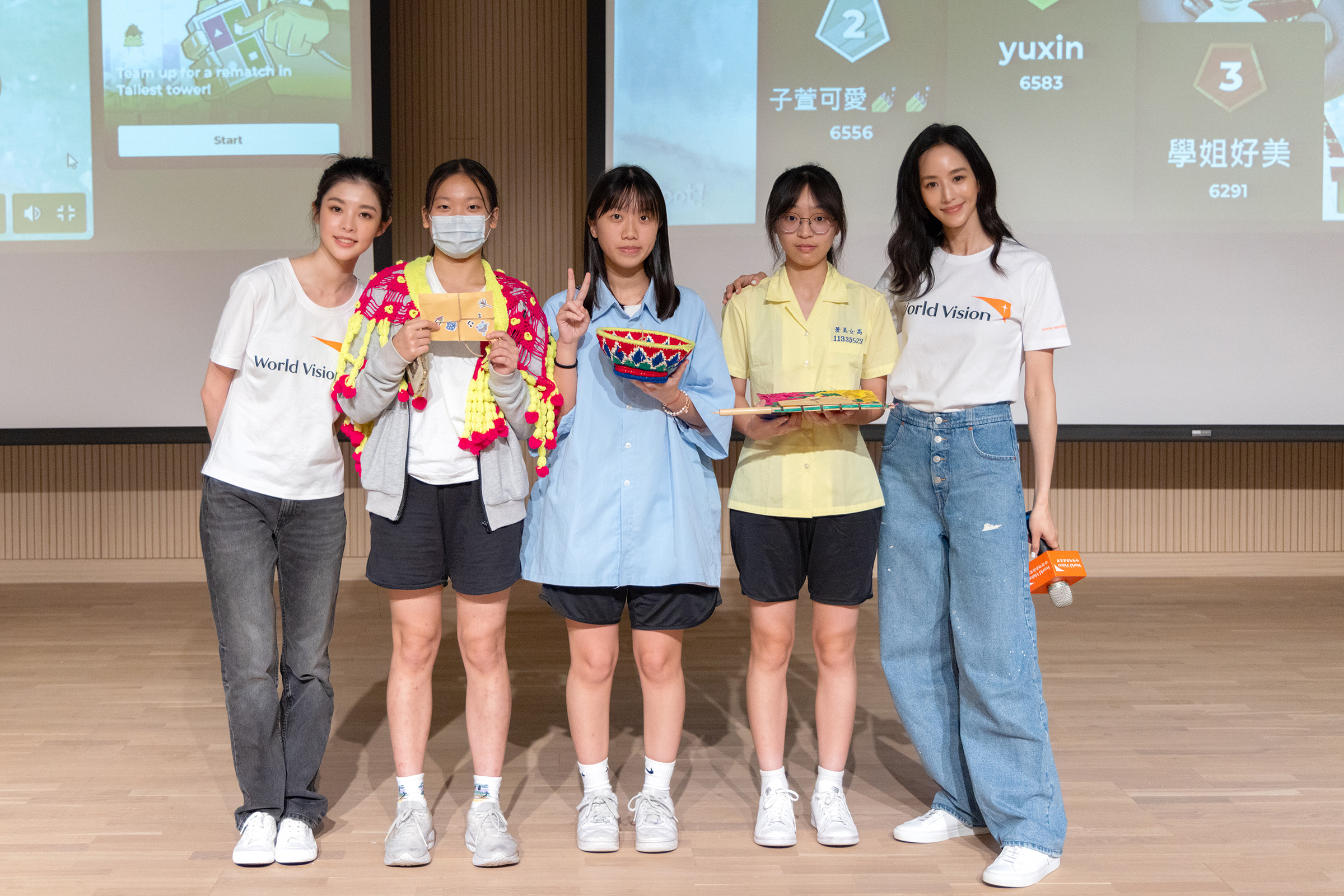 張鈞甯與她旗下新人詹子萱以代言人身分回到其母校景美女中，為脆弱女孩發聲，並送上尼泊爾媽媽手作的特色織品給同學。（台灣世界展望會提供）