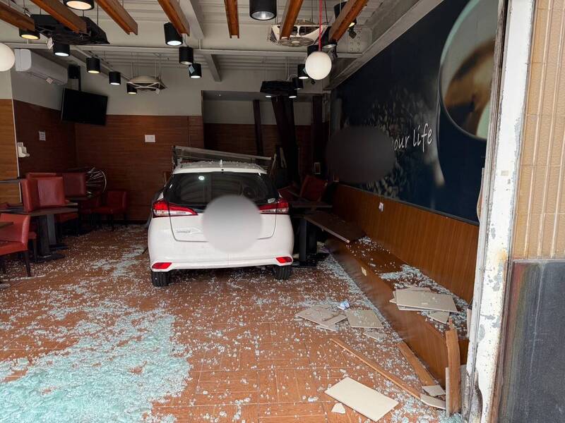 白色轎車撞破85度C落地窗玻璃，也將桌椅撞爛。（翻攝畫面）