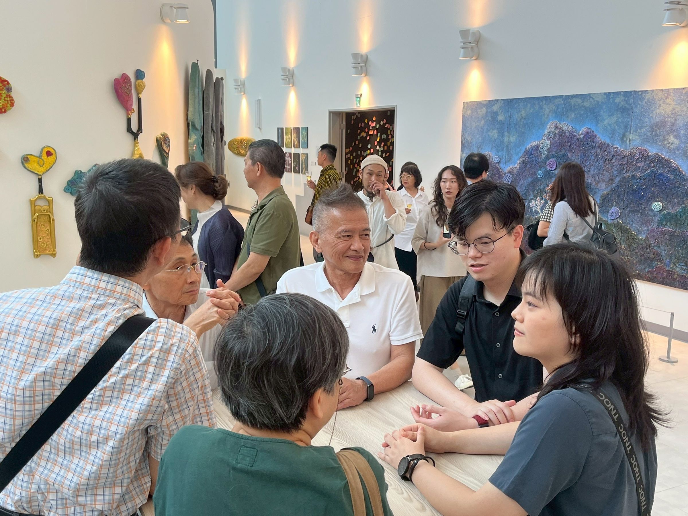 現場氣氛熱絡，藝術家曾英棟（白衣者）與嘉賓相談甚歡。（甘樂阿舍美術館提供）