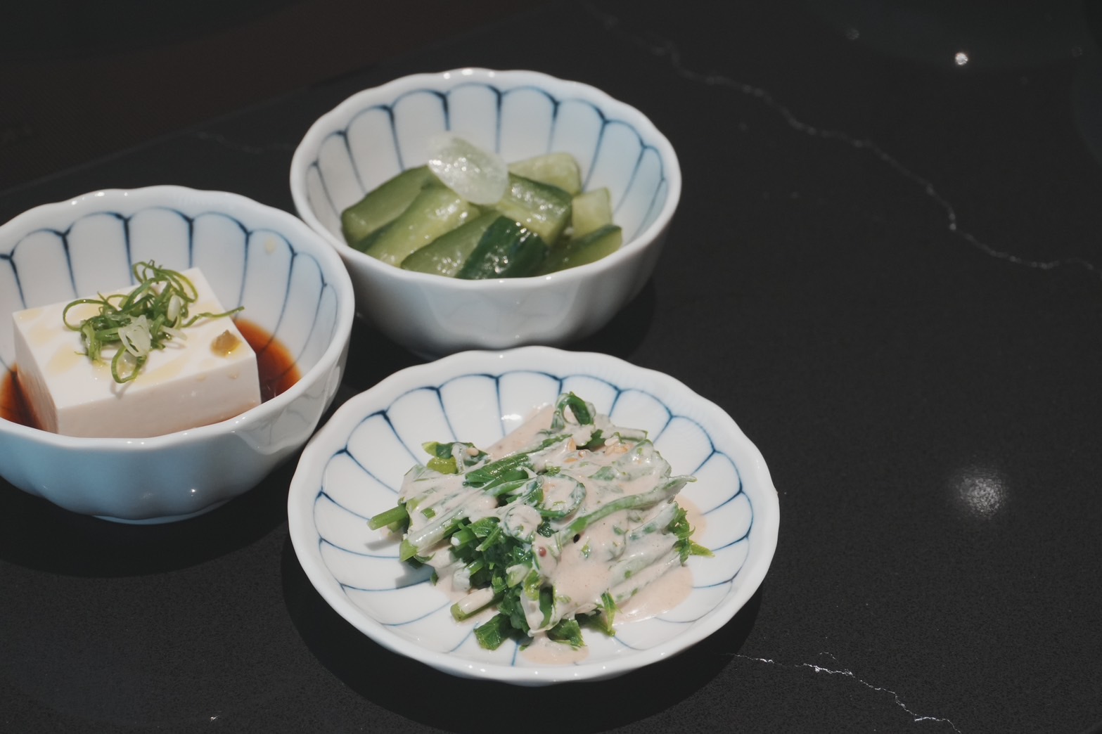 前菜的「胡麻過貓」（下）搭配胡麻醬，適合在食用火鍋時轉換口味；「日式湯豆腐」（左）點入自製的煙燻橄欖油與柚子胡椒增添層次；「香麻拌黃瓜」（上）在熟悉的蒜香中加入特製花椒油，清爽解膩。