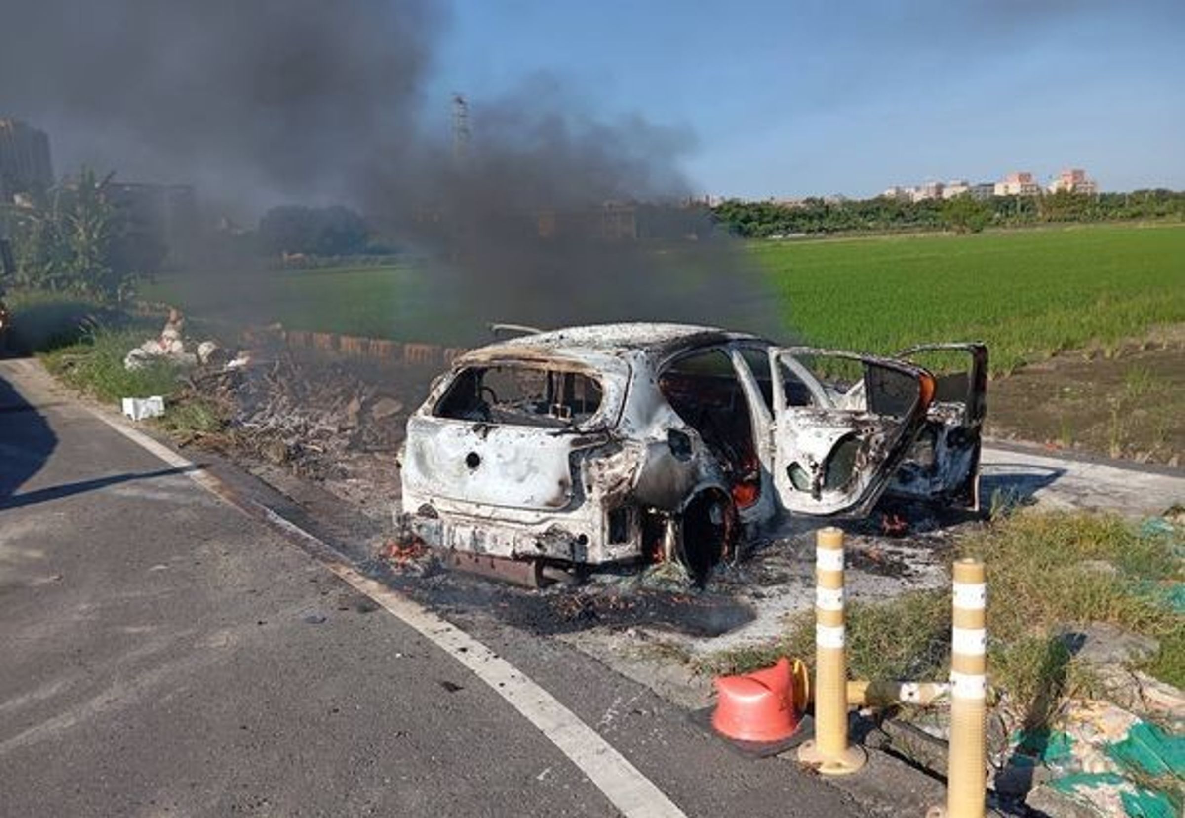 槍手駕駛白色BMW X1逃逸後縱火棄車,現場焦黑車殼駭人。(翻攝畫面)