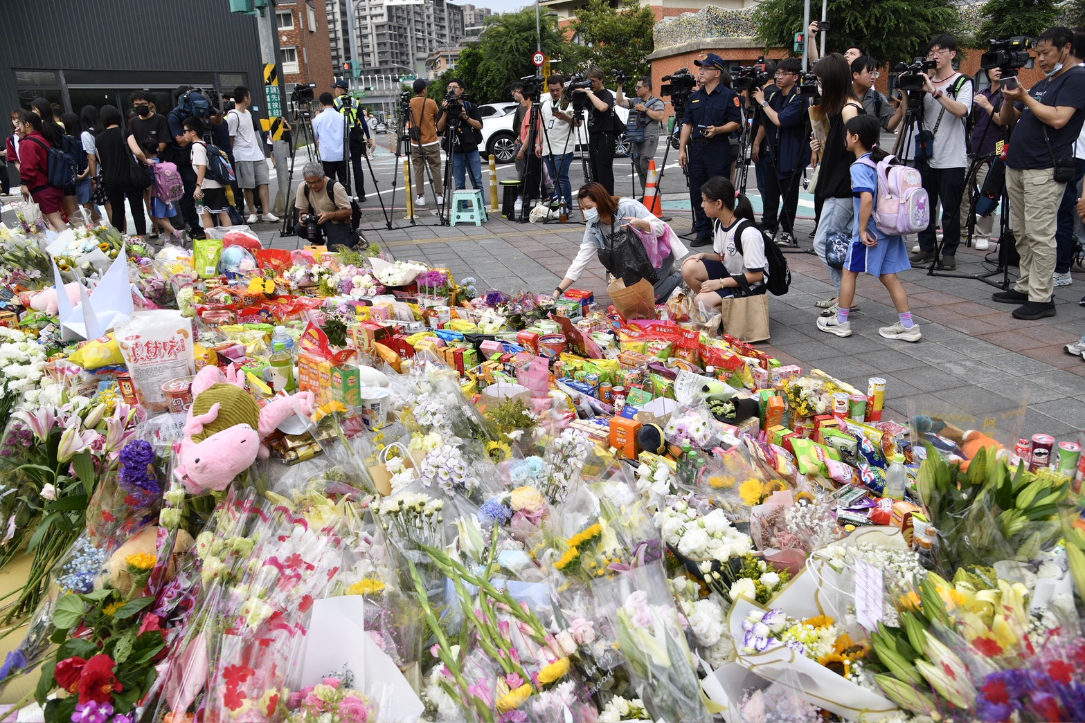 三峽車禍悼念現場湧入民眾擺滿鮮花與玩偶，但人行道卻被違停車輛占據，引發熱議。（鏡報新聞網李智為）