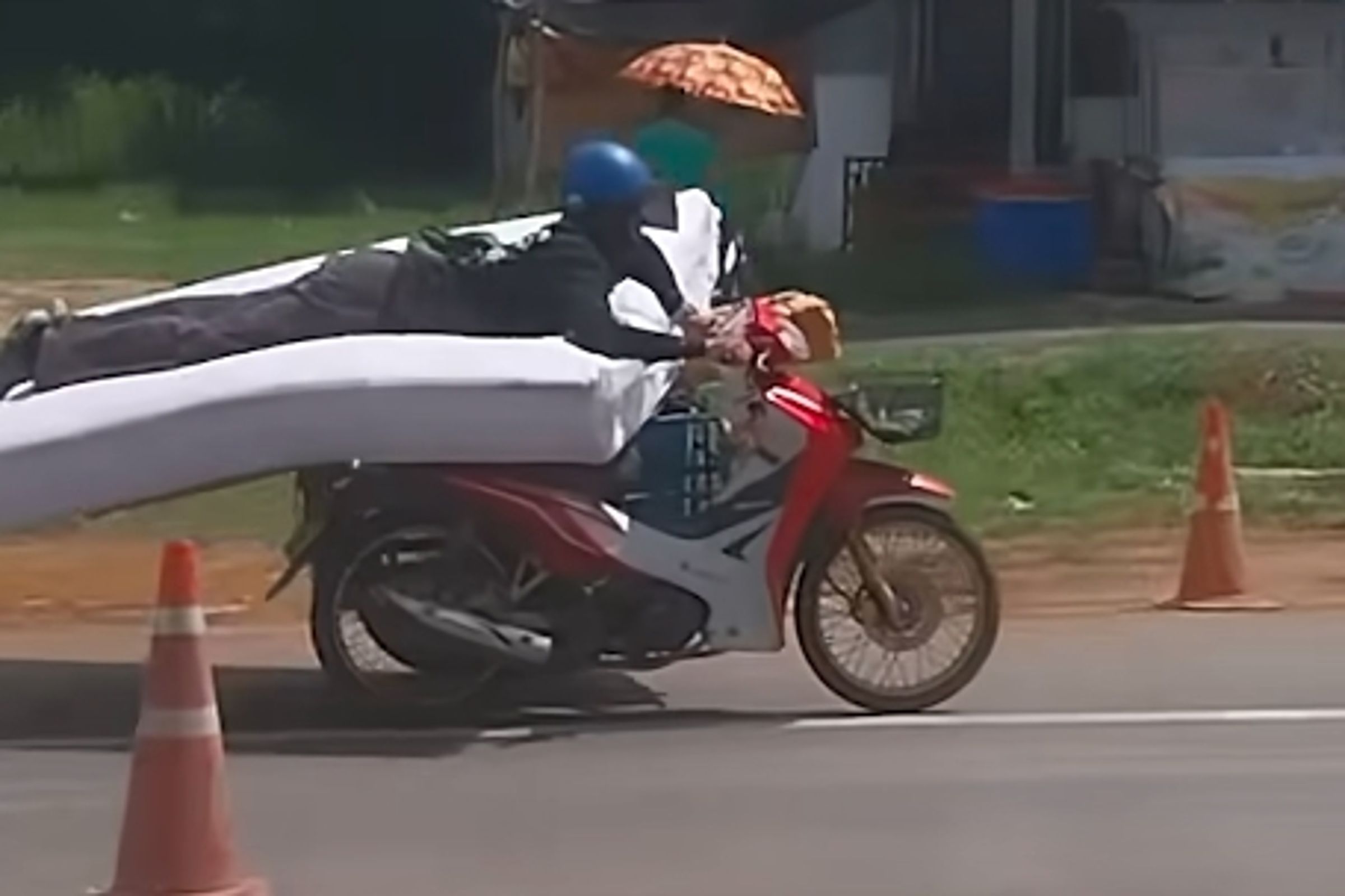 一名男子趴在床墊上騎機車,姿勢相當特殊,引起網友熱烈討論。(翻攝畫面)