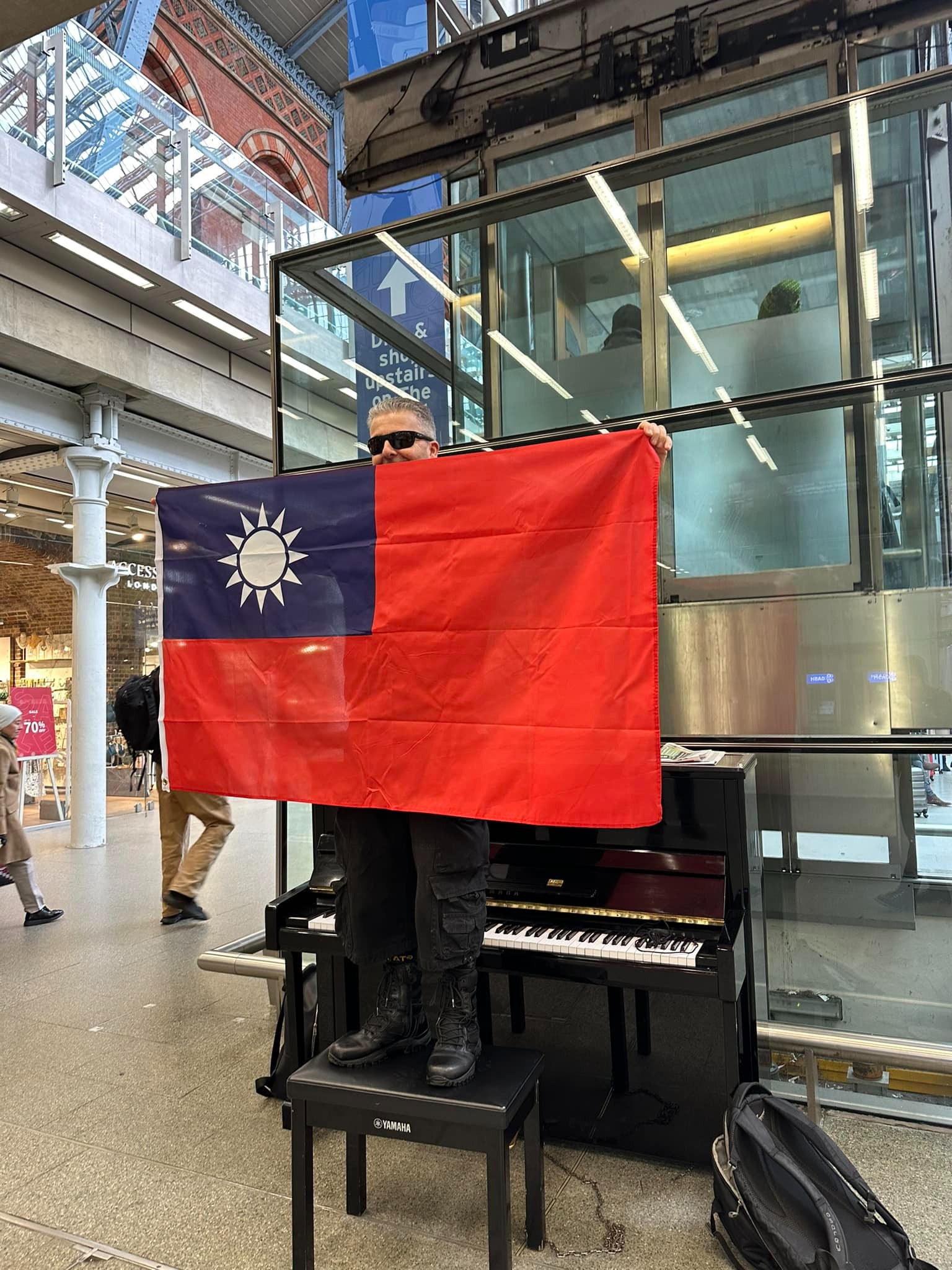 英國鋼琴家卡瓦納在倫敦聖潘克拉斯車站高舉中華民國國旗。（翻攝自Dr K Boogie Woogie臉書）