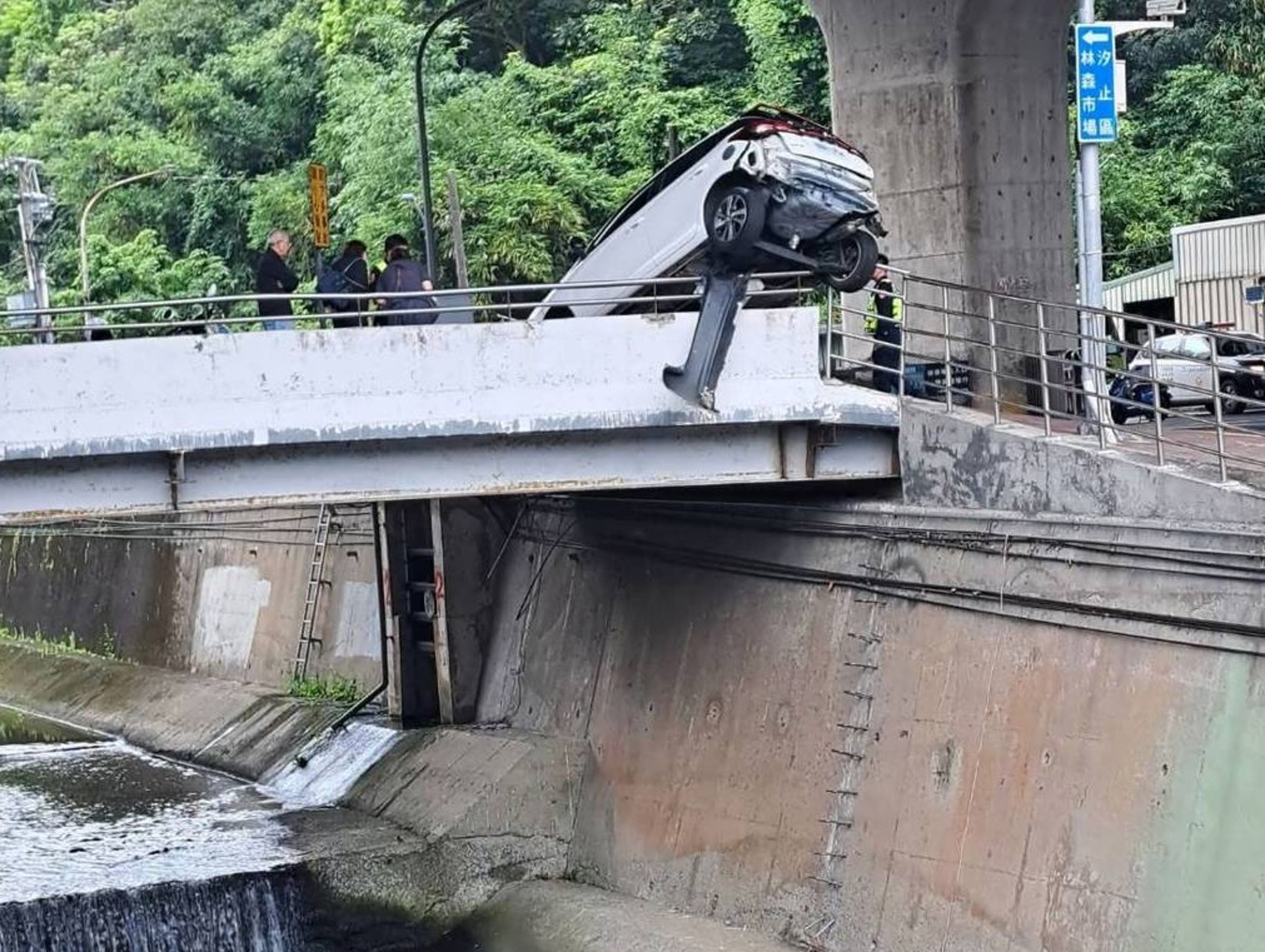 該輛自小客車卡橋邊，後車輪整個懸空，差一秒就要墜落溪床。（翻攝自記者爆料網）