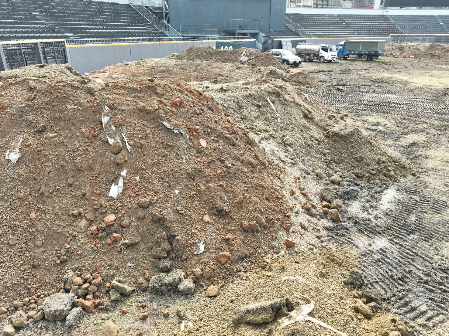 新竹市立棒球場啟動覆土移除作業後，外野區域挖出大量混凝土石塊，夾雜塑膠製品、廢電線、紅磚等營造廢棄物。（讀者提供）
