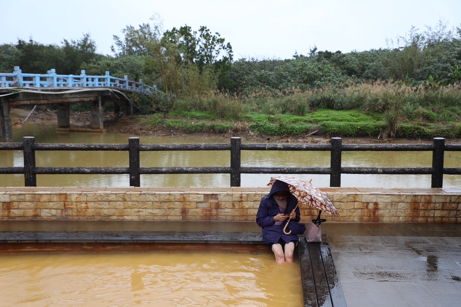 即使天空飄著毛毛細雨，遊客依然甘願撐傘享受泡腳池的暖熱湯泉。