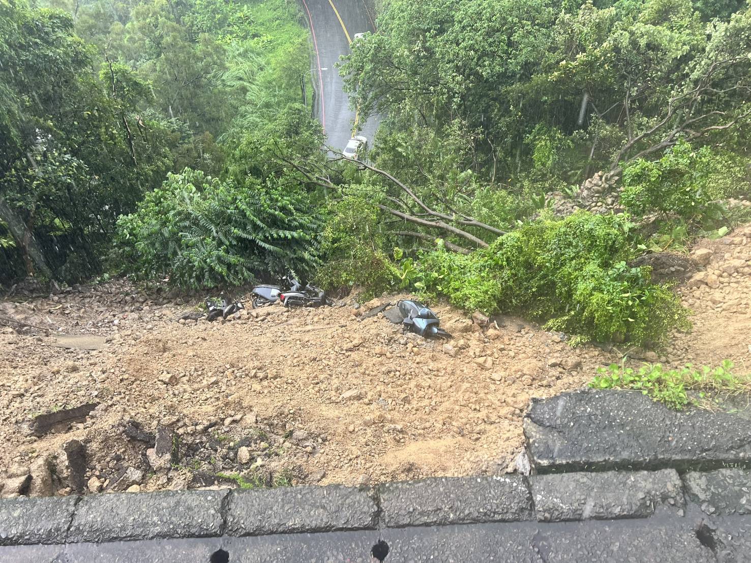 新北市新店區新坡一街,今日午後因強降雨導致路基遭掏空,路面出現巨大崩裂缺口。(翻攝畫面)