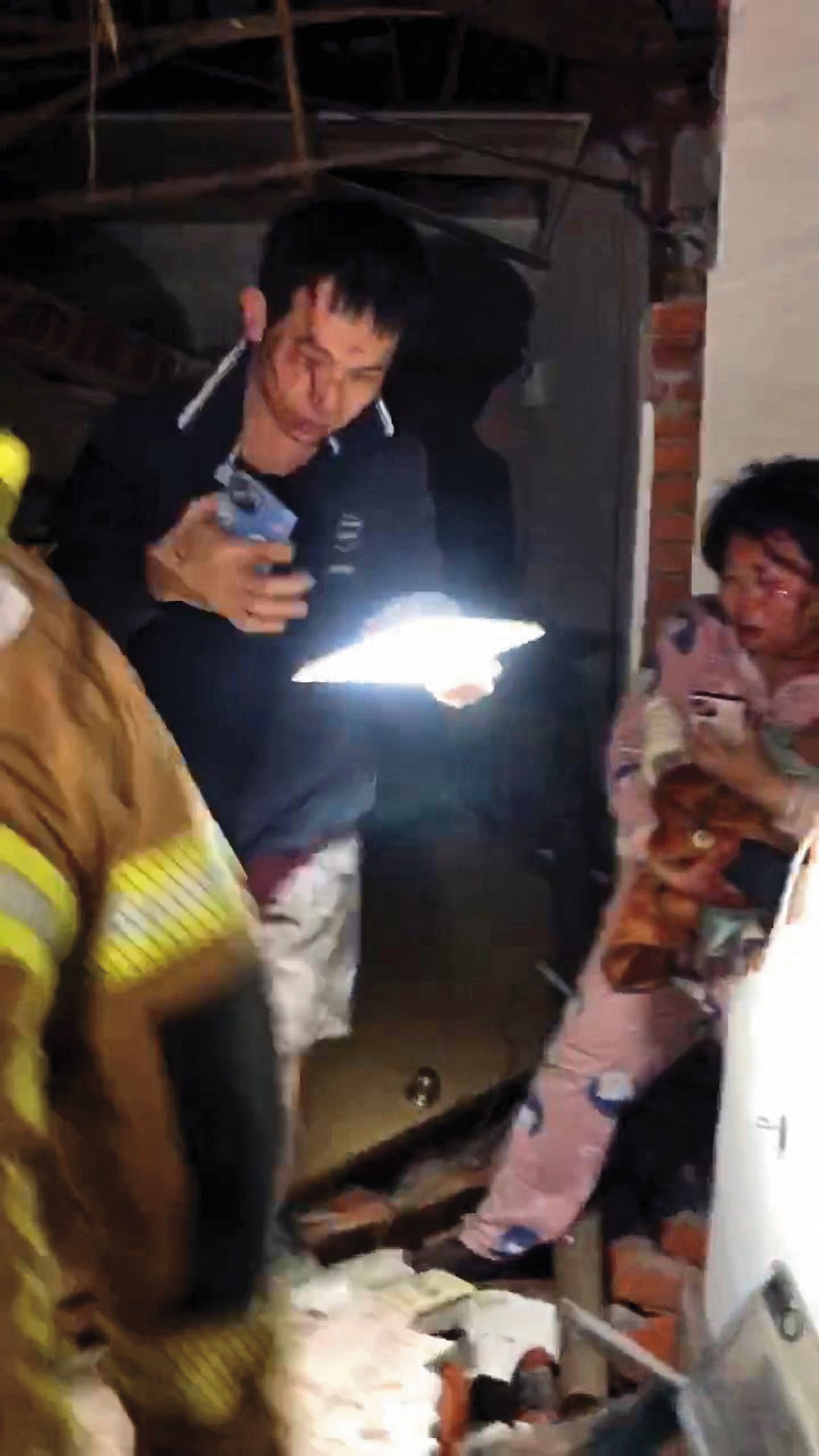 消防員破門進入台南楠西區民族路上的倒塌民宅，救出受困屋內的男女及幼兒。（台南市消防局提供）