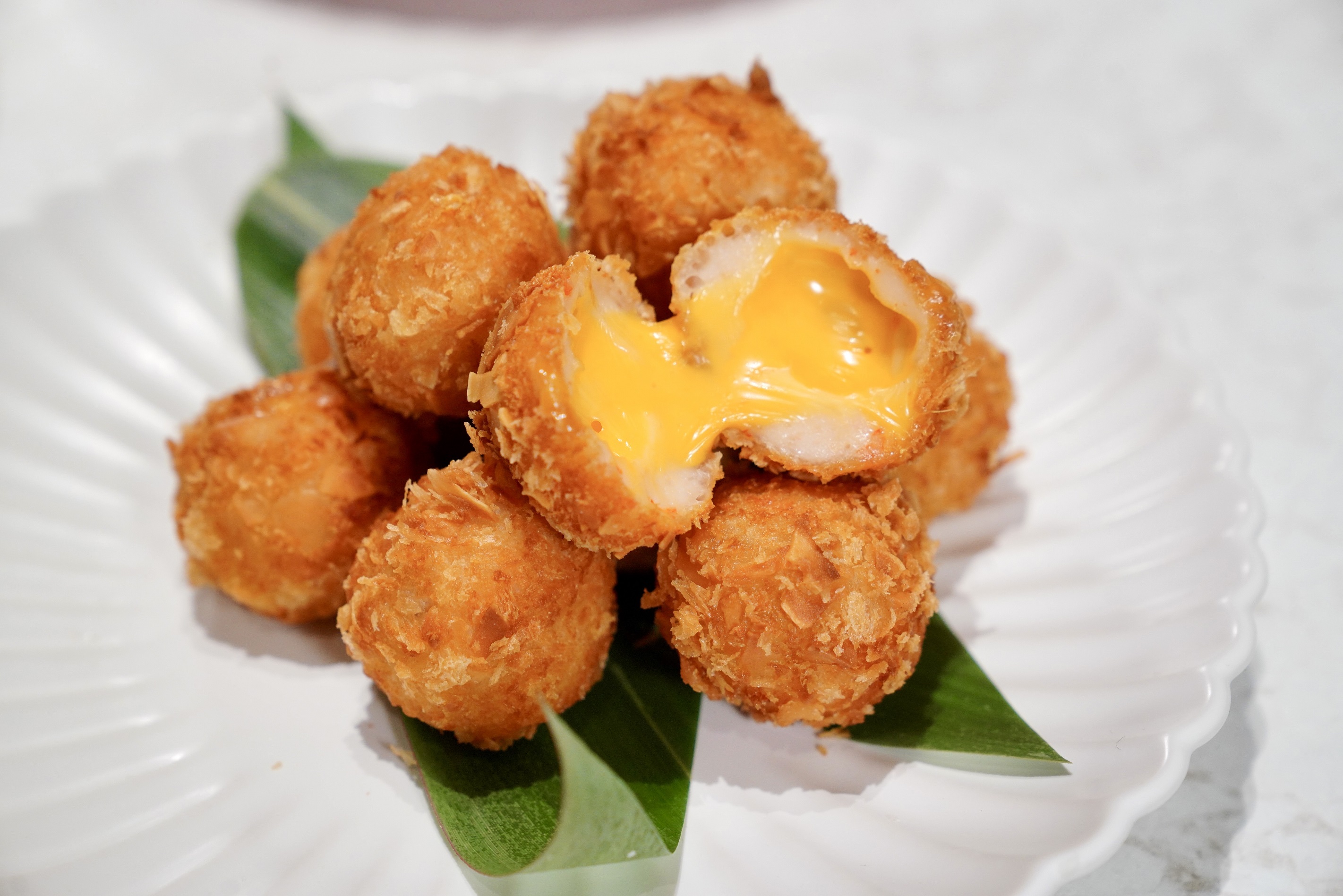 採用林口在地食材紫地瓜製成的〈椰香紫薯流金球〉，外酥內爆漿，椰香與起司交織甜蜜滋味。（攝影組）。