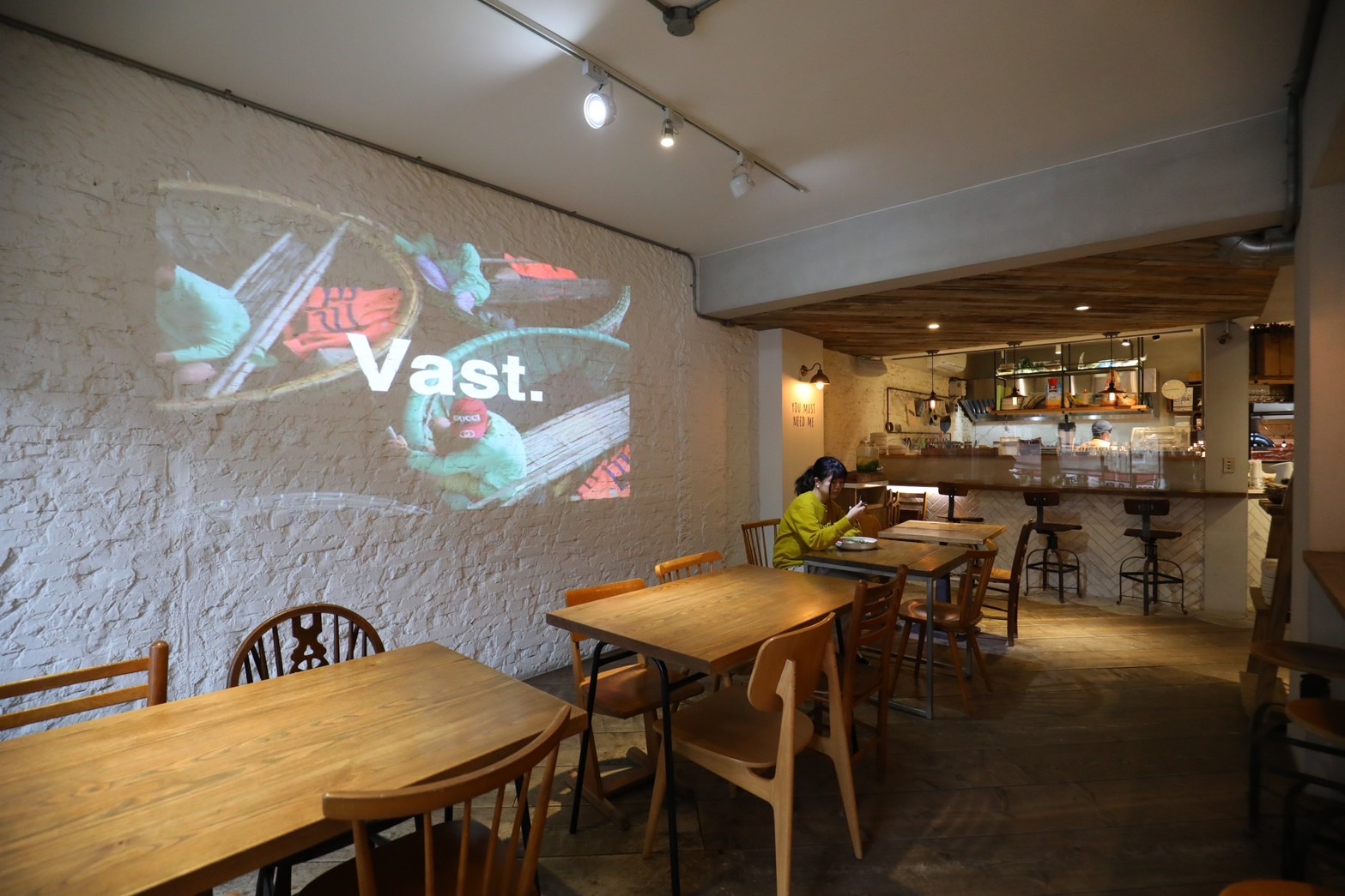 店內座位區牆上用投影機撥放著關於「VAST Cali Eatery」的品牌理念影片。
