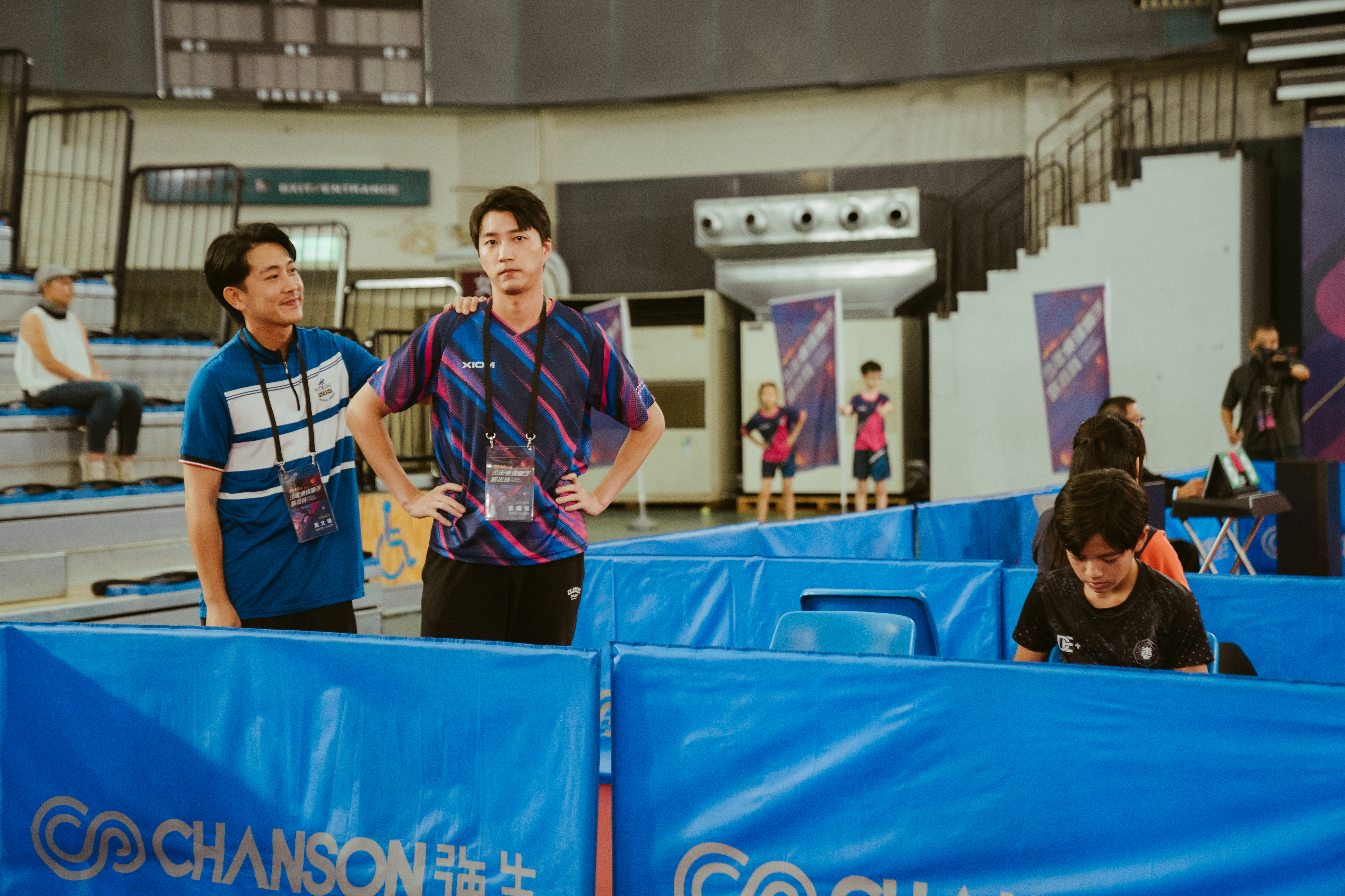 施名帥（左起）、江宏傑，分別飾演作風炯然不同的桌球教練，不只在場上競爭，鏡頭外也經常練習。（華納兄弟提供）