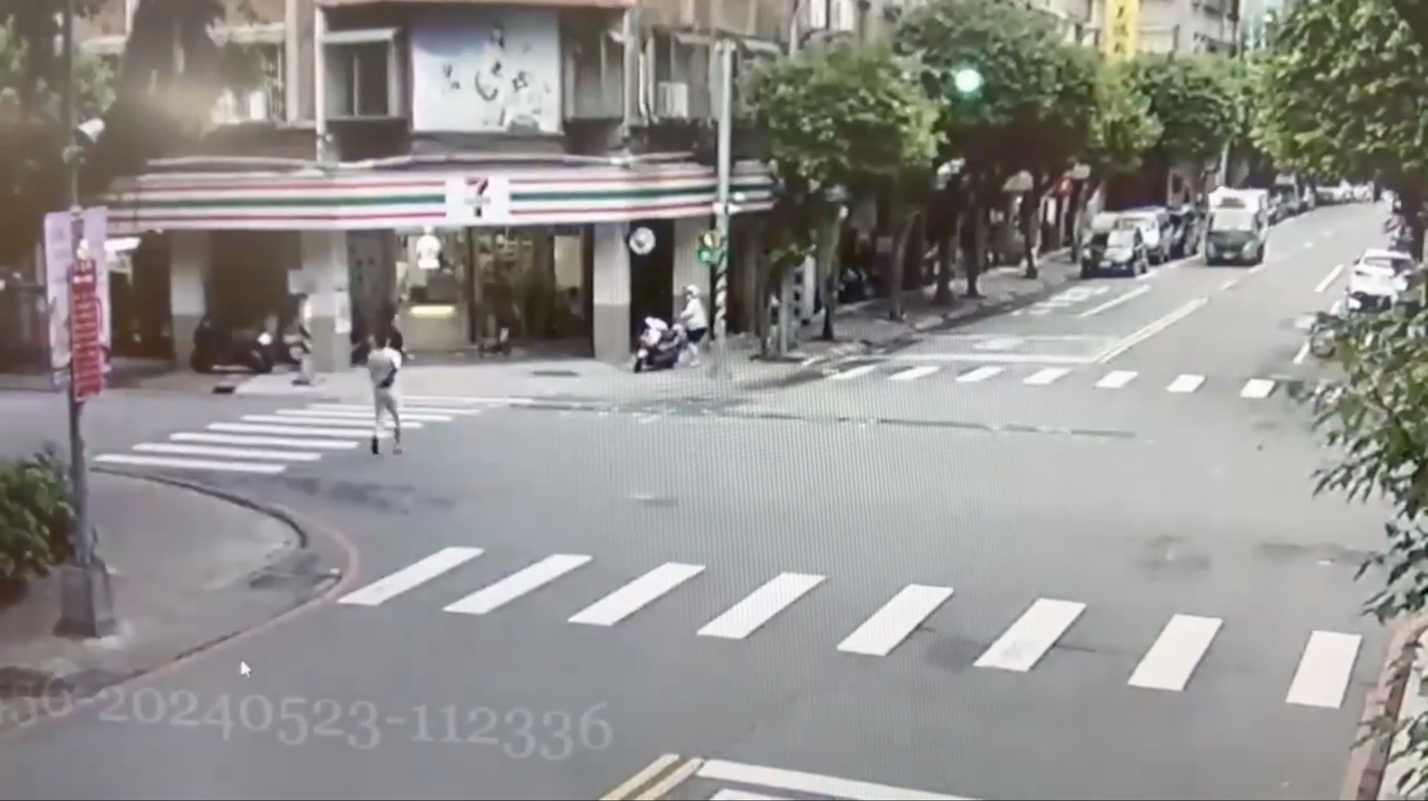 遭砍後，彭男（白衣者）在友人陪同下穿越馬路。（翻攝畫面）