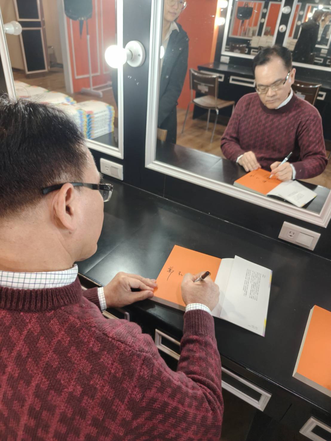 鄭弘儀在《新聞挖挖哇》後台低頭狂簽書,飯都來不及吃。(紙風車劇團提供)