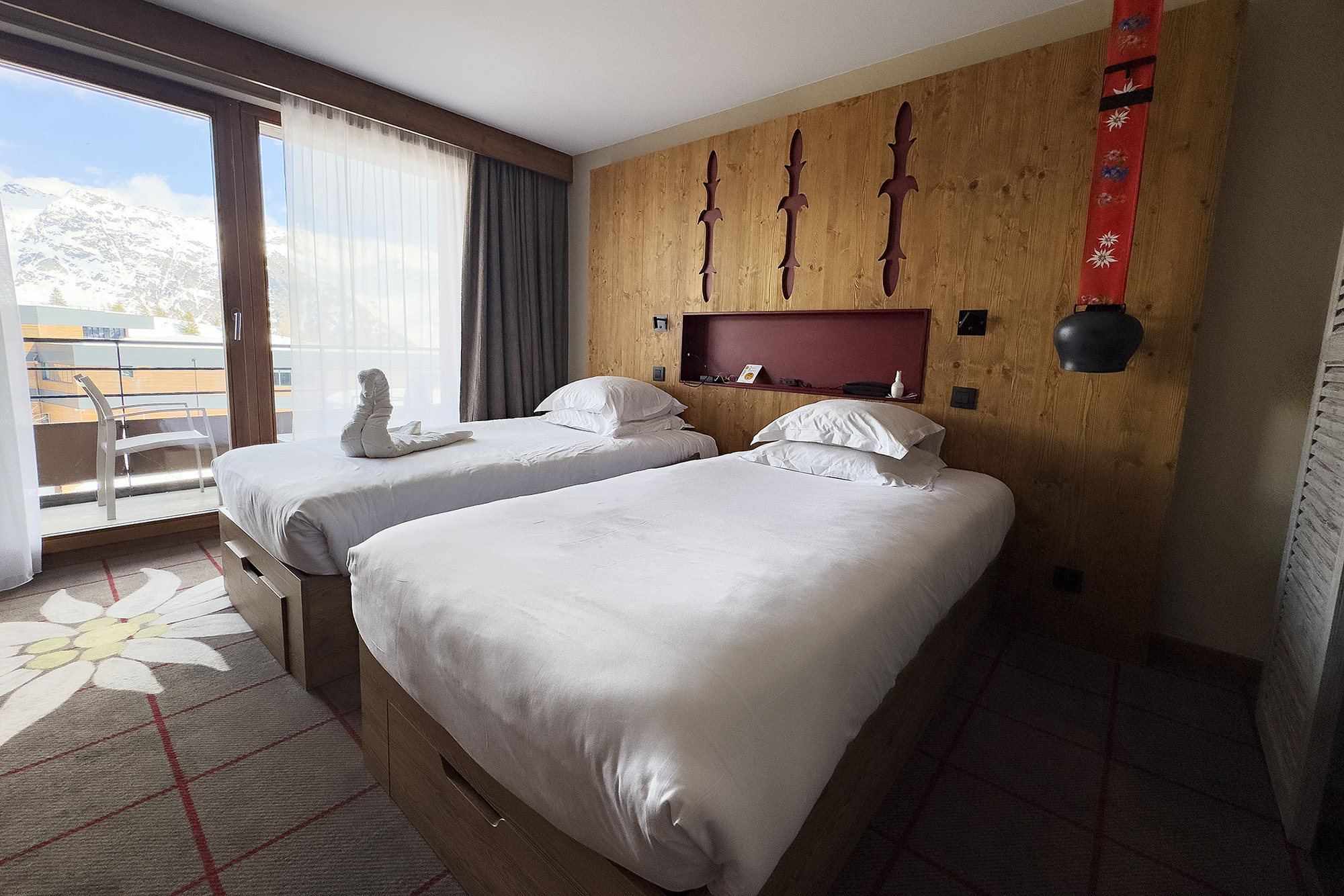 Club Med La Rosière的客房融合阿爾卑斯風格的溫馨客房內部陳設，床頭燈有牛鈴造型特色。