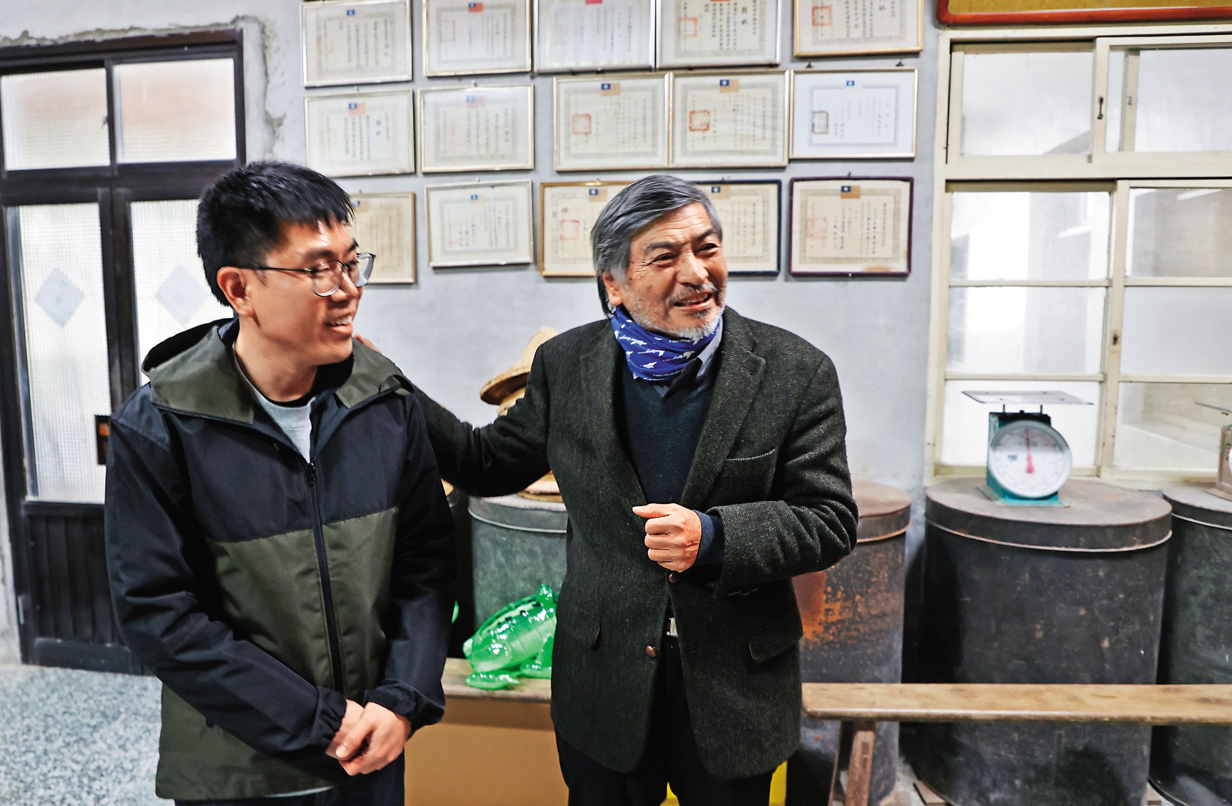 在老茶廠裡,郭明政(右)向我們介紹茶廠的第五代製茶師張恩沛(左)。