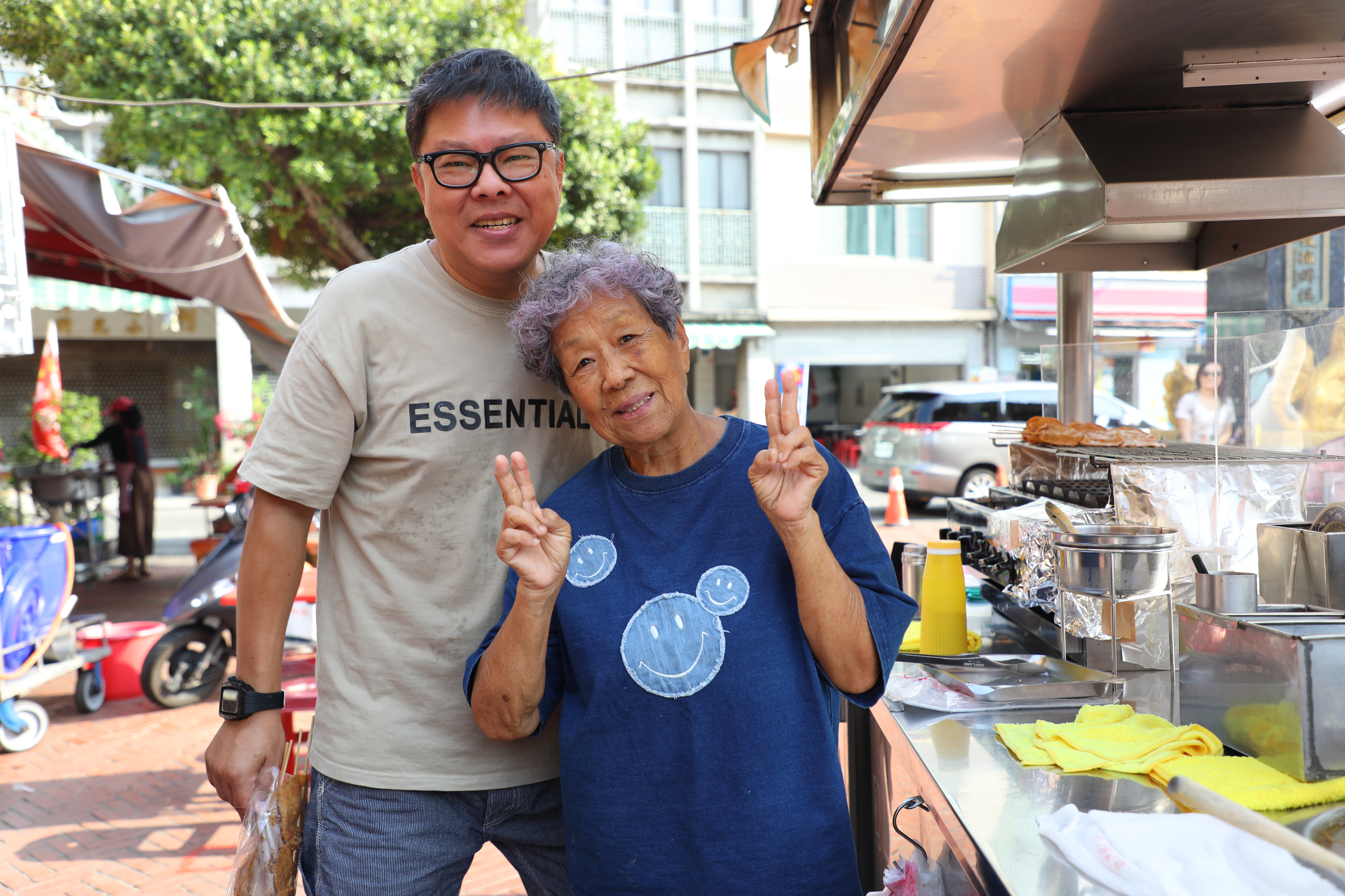 本在台北工作的董育騰（左）現在回家鄉與媽媽阿蘭（右）一同經營小攤，母子倆一個調麵線焿，一個烤黑輪，合作無間。