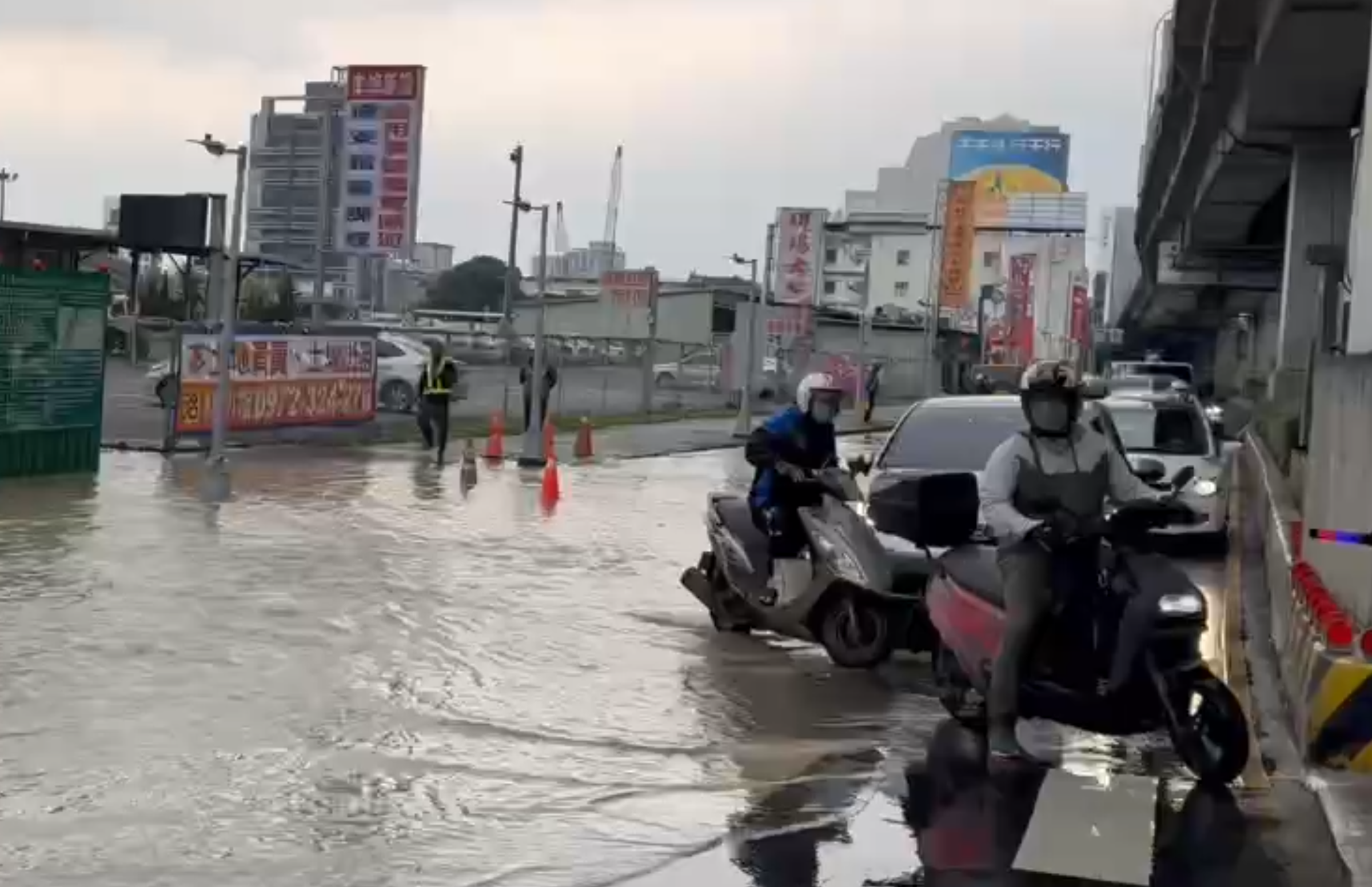 由於大量自來水淹至新北大道，汽機車只能由內側車道涉水緩慢通行，警方現場已封路交管。（翻攝畫面）