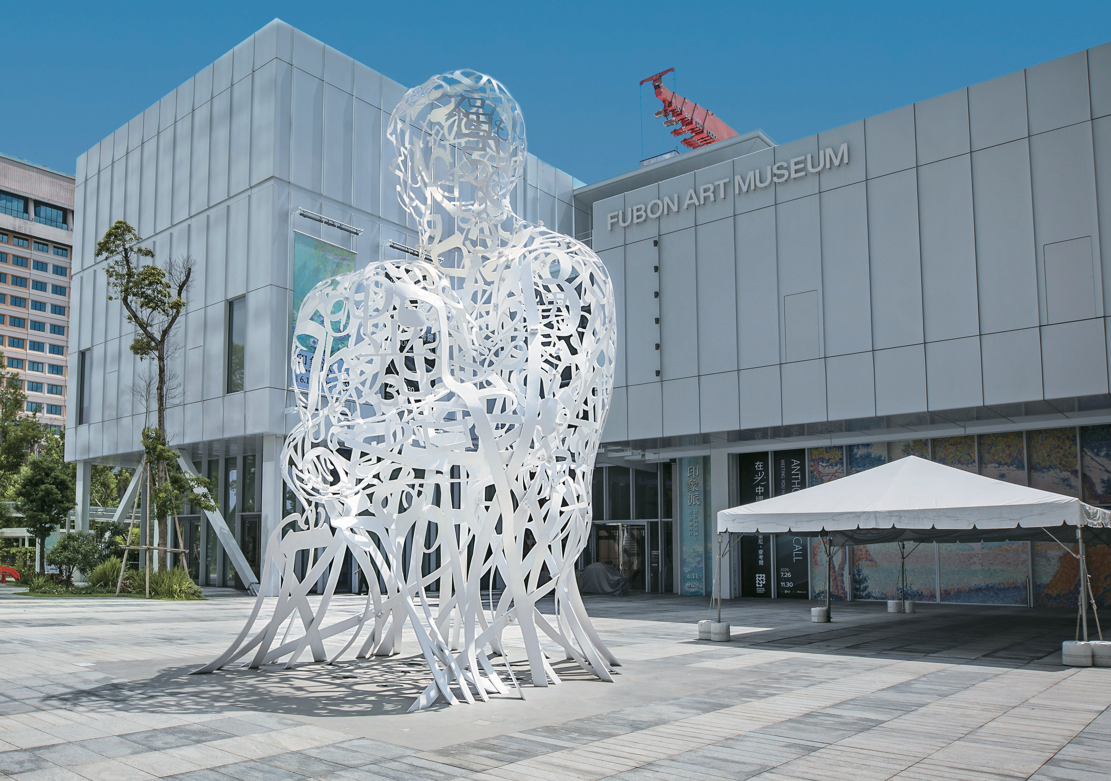 美術館的白色立方體建築與光影交織的鏤空人形雕塑相互映襯。