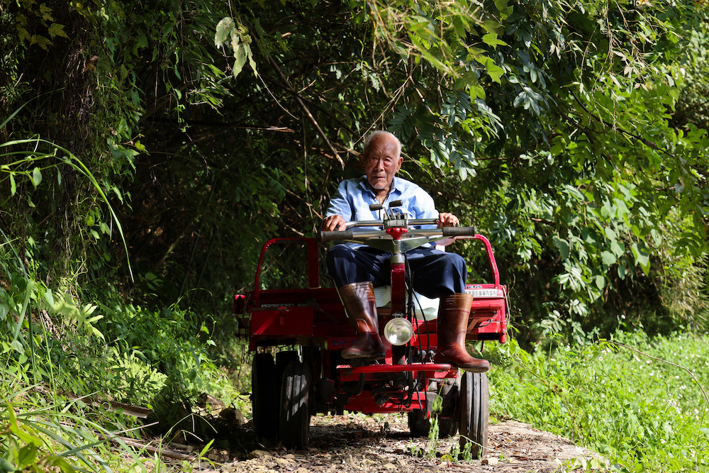 現年98歲的耆老郭火炎儘管行動不便，仍堅持駕駛著鐵牛，持續守護賴以維生的山林。（春雷創意提供）