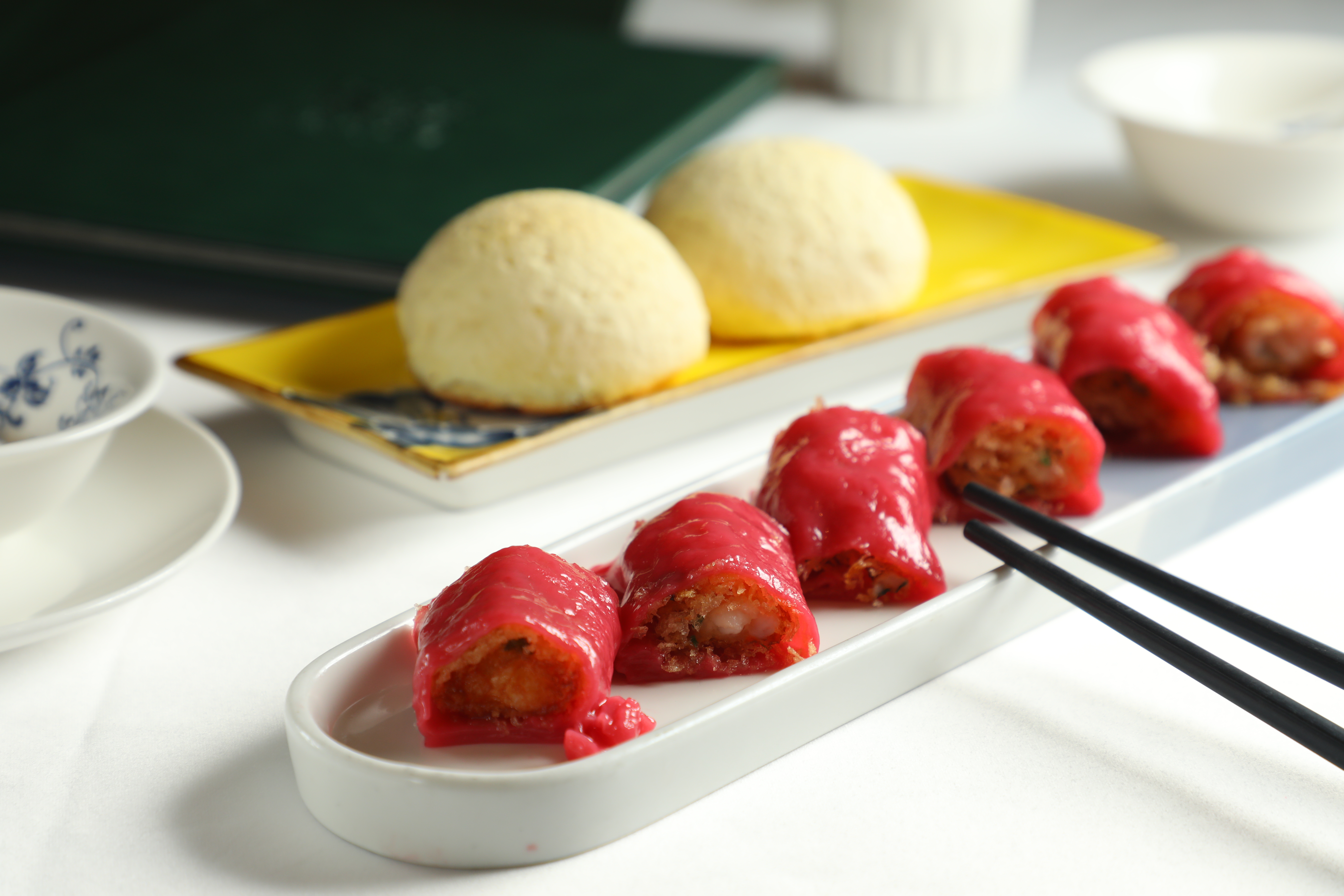 「香脆明蝦紅米腸粉」（前，港幣78元／份，約NT$290）「雪山黑毛豬焗餐包」（後，港幣58元／份，約NT$216）都是點心主廚的拿手好戲，只在午間供應。