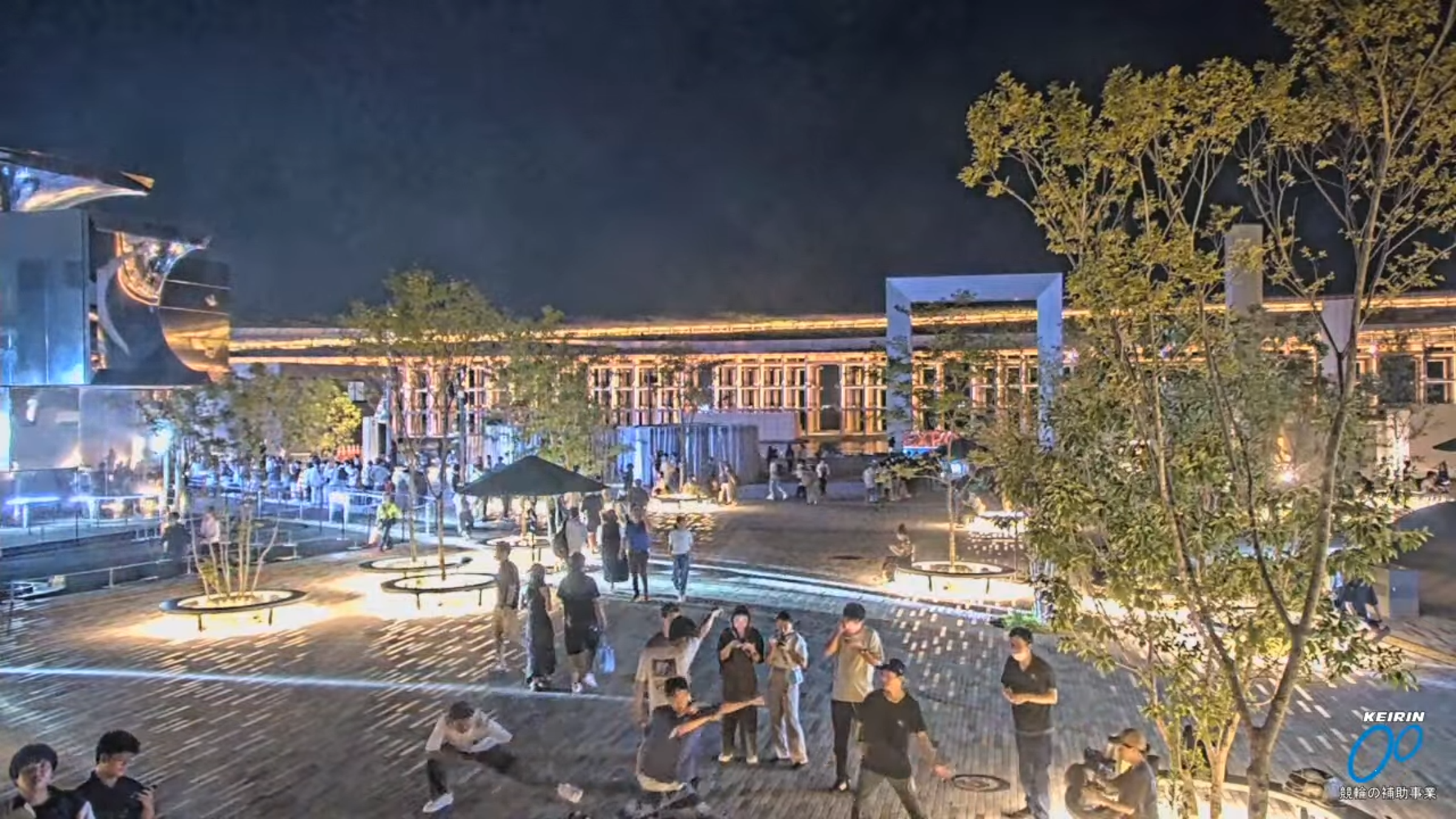 大批人潮等著進去臨時開放的場館,年輕人苦中作樂對著直播鏡頭跳舞。(翻攝自@Expo2025-Live-Camera YouTube)